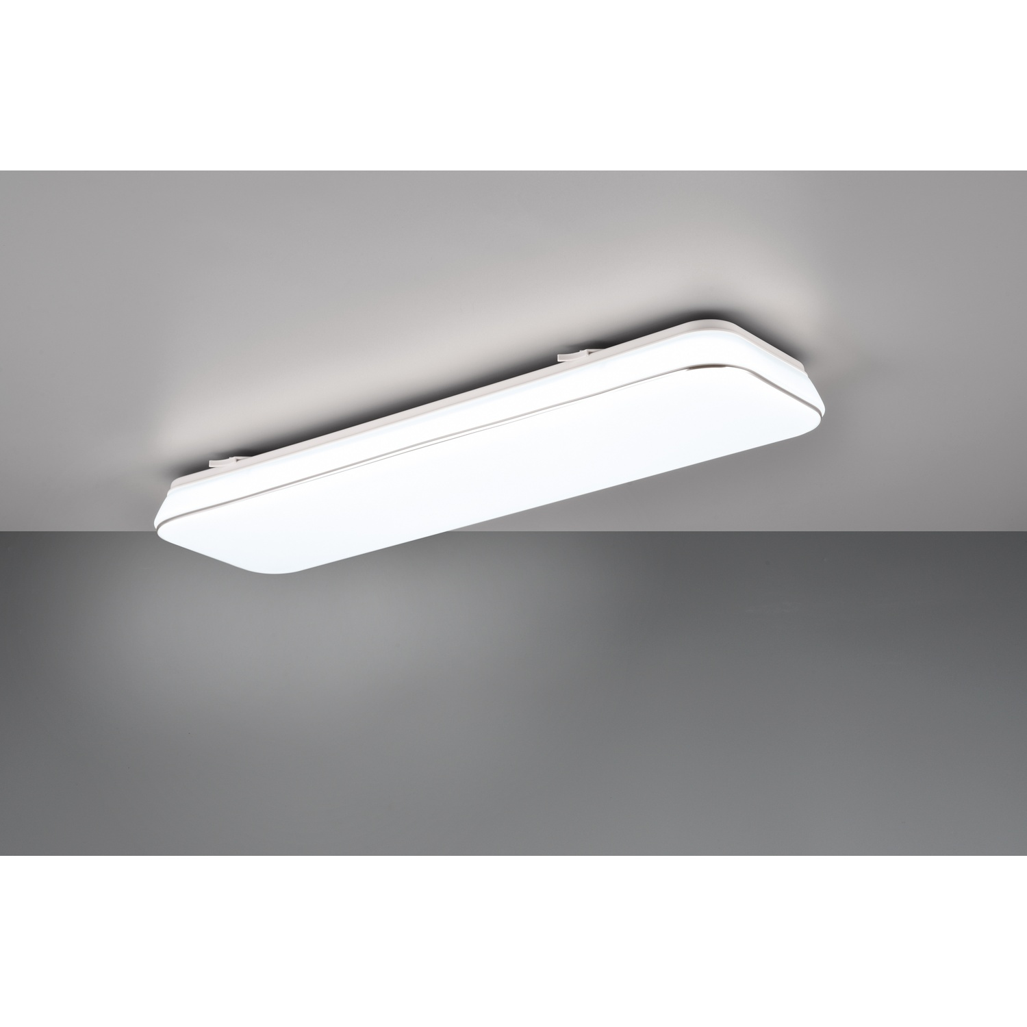 Luce da soffitto rettangolare bianca, montata su un soffitto grigio. È un pannello lungo e piatto.