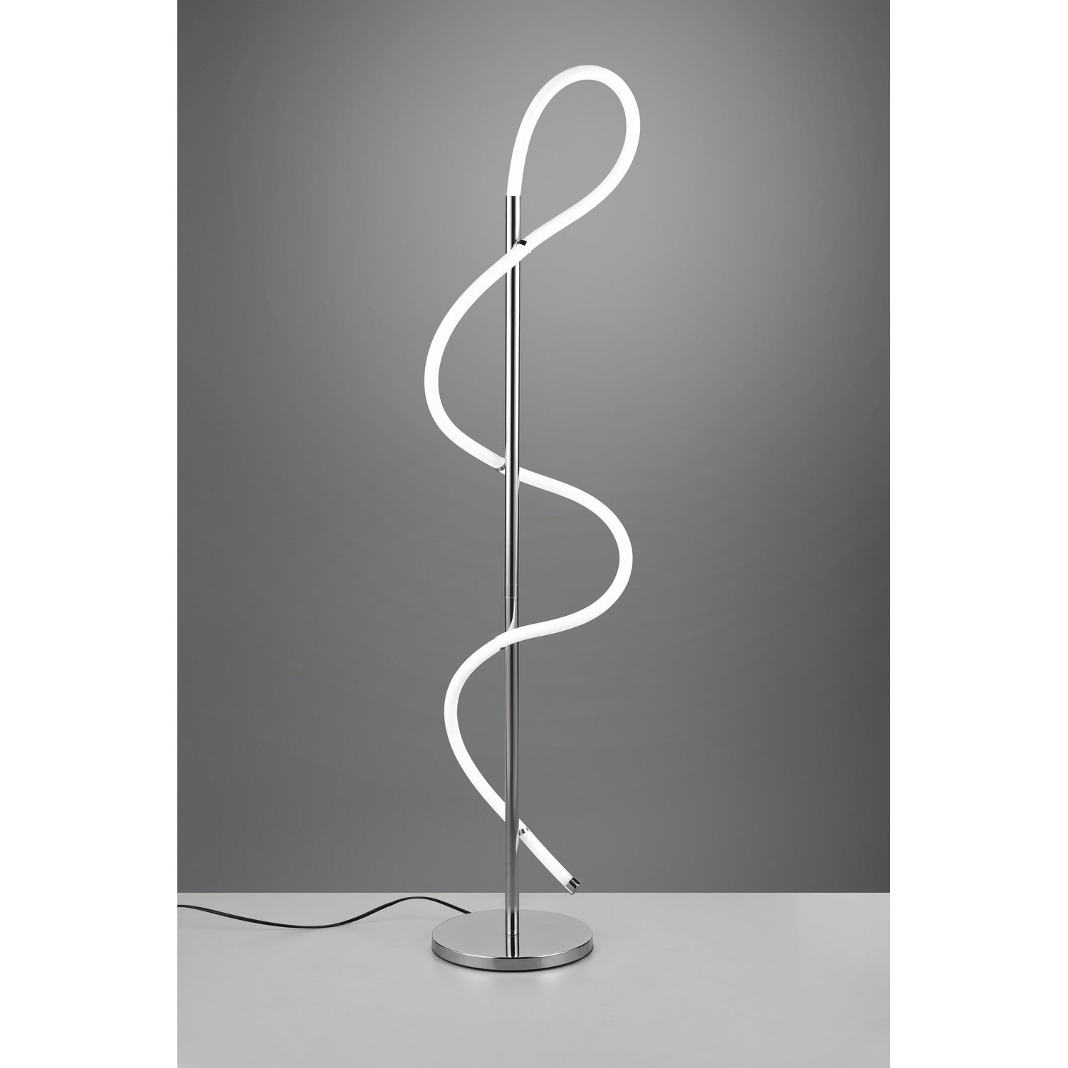 Una lampada da terra argentata con una luce al neon bianca a spirale. Si trova su una superficie bianca.