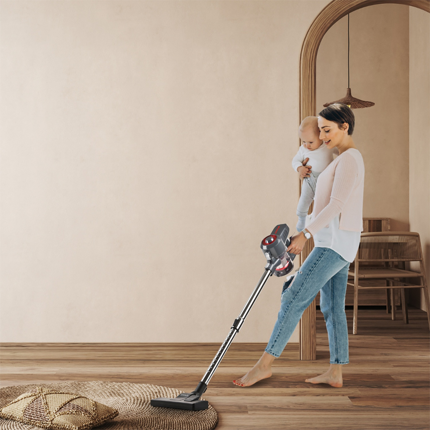 Donna che passa l'aspirapolvere tenendo un bambino, accanto a un tappeto rotondo. Interno.