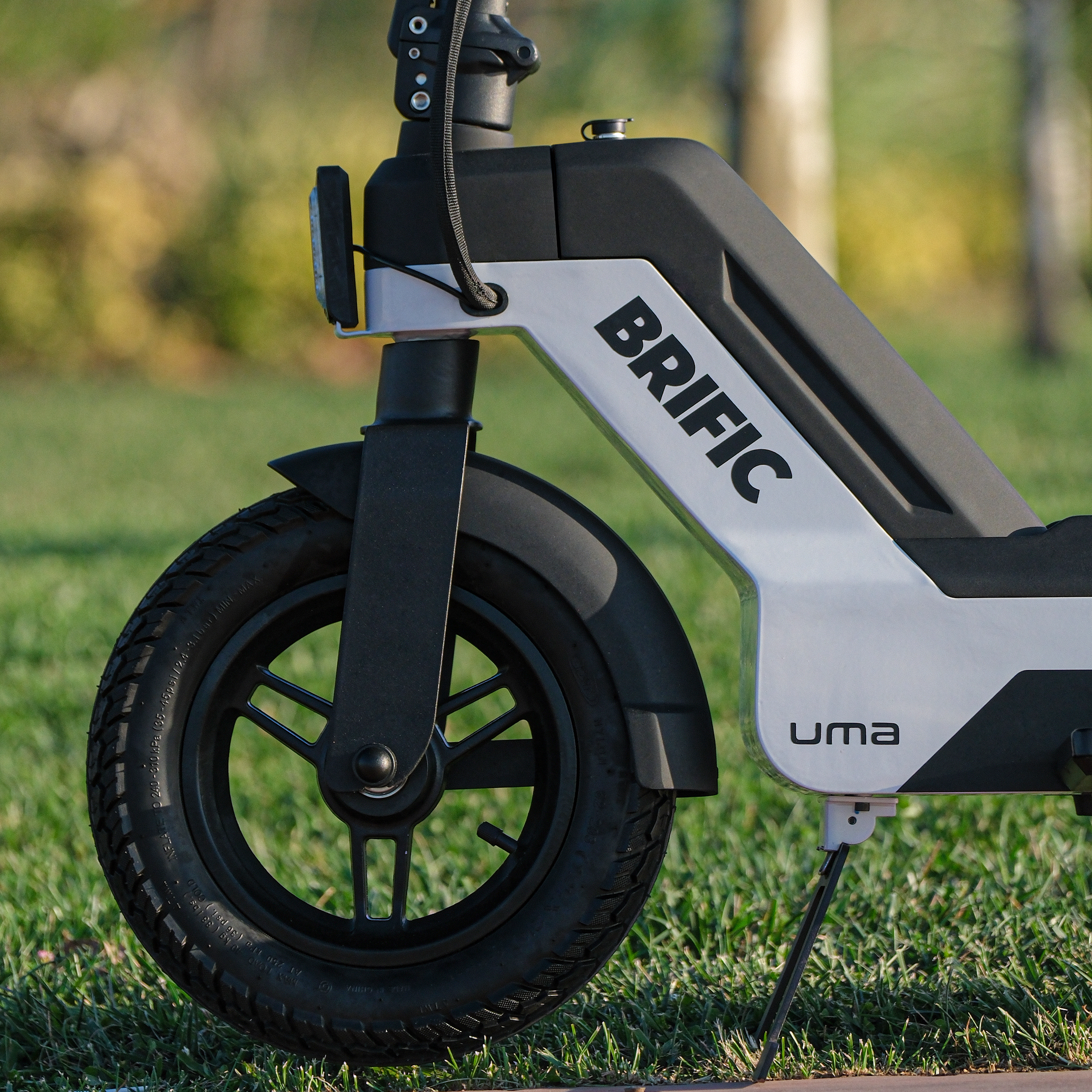 Çim üzerinde bir elektrikli scooter tekerleğinin yakın çekimi, marka adını ve lastik detayını gösteriyor.