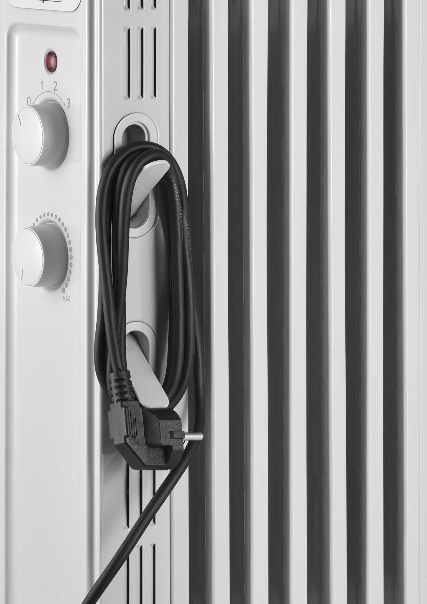 Egy fehér elektromos fűtőtest közelképe, rajta egy fekete tápkábellel.