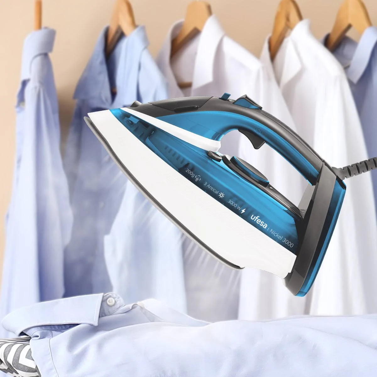 Una plancha vaporizando una camisa azul, con otras camisas colgadas en el fondo.