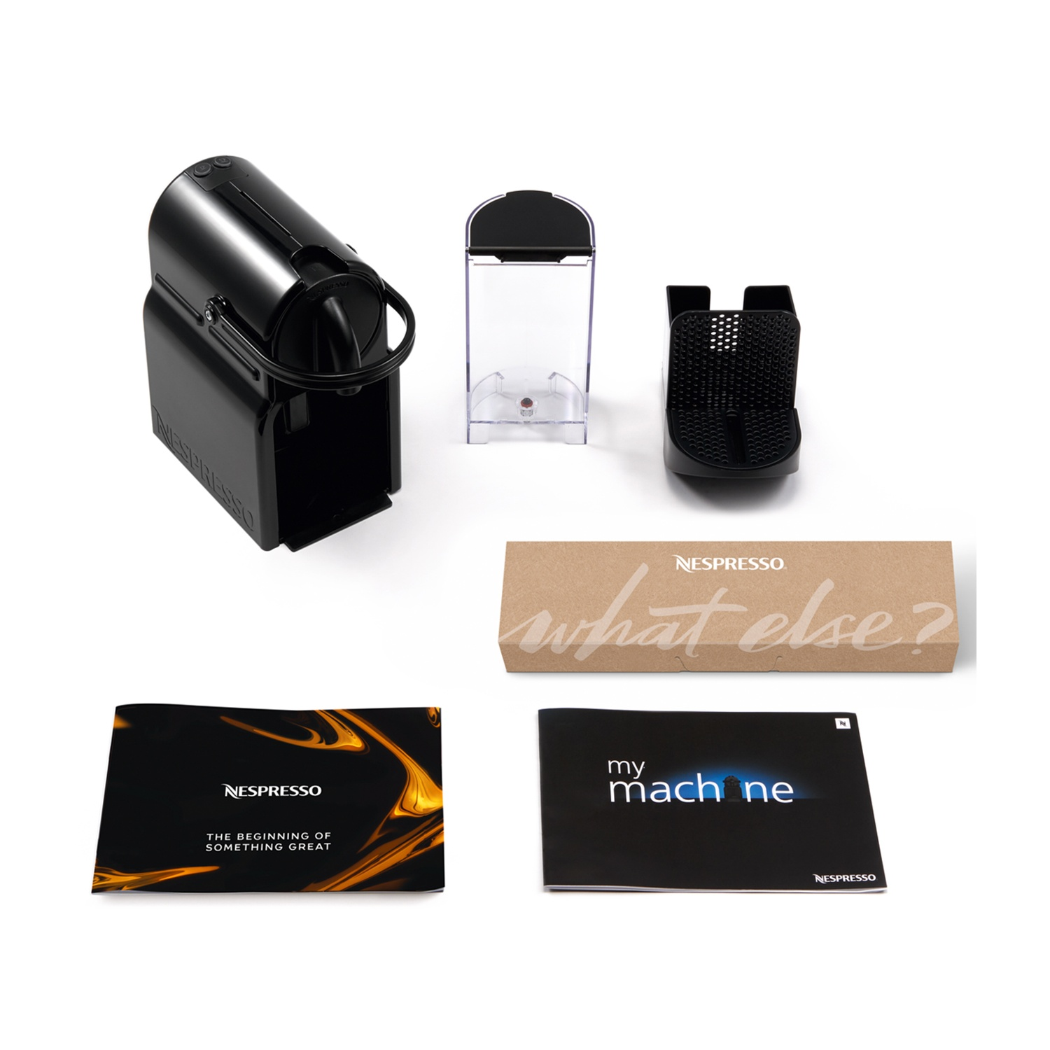 Vari componenti della macchina Nespresso disposti su una superficie bianca. Include la macchina, il serbatoio dell'acqua e i manuali.