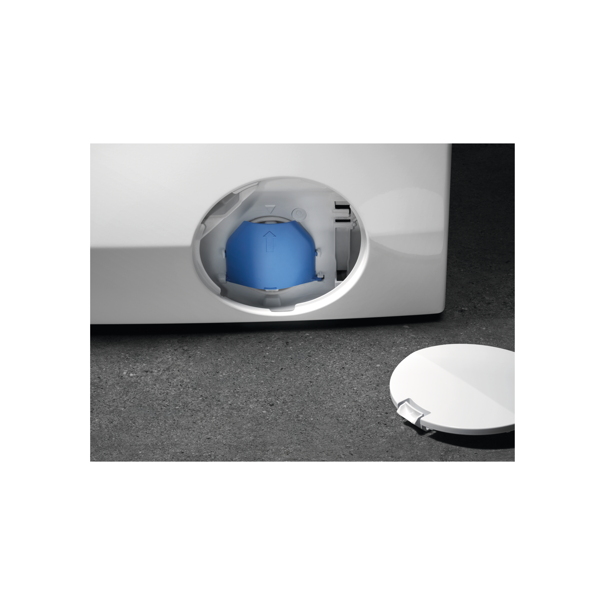 A close-up of a washing machine's drain with a blue cap inside, and the white cover.