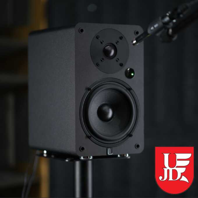 Czarny głośnik audio jest zamontowany na statywie, z mikrofonem.