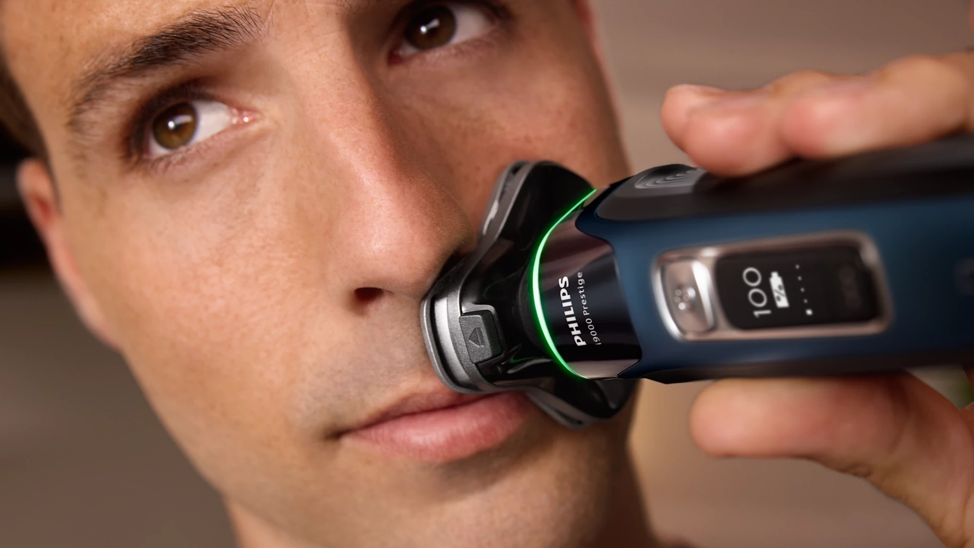 Mężczyzna goli twarz golarką elektryczną Philips. Ujęcie z bliska.