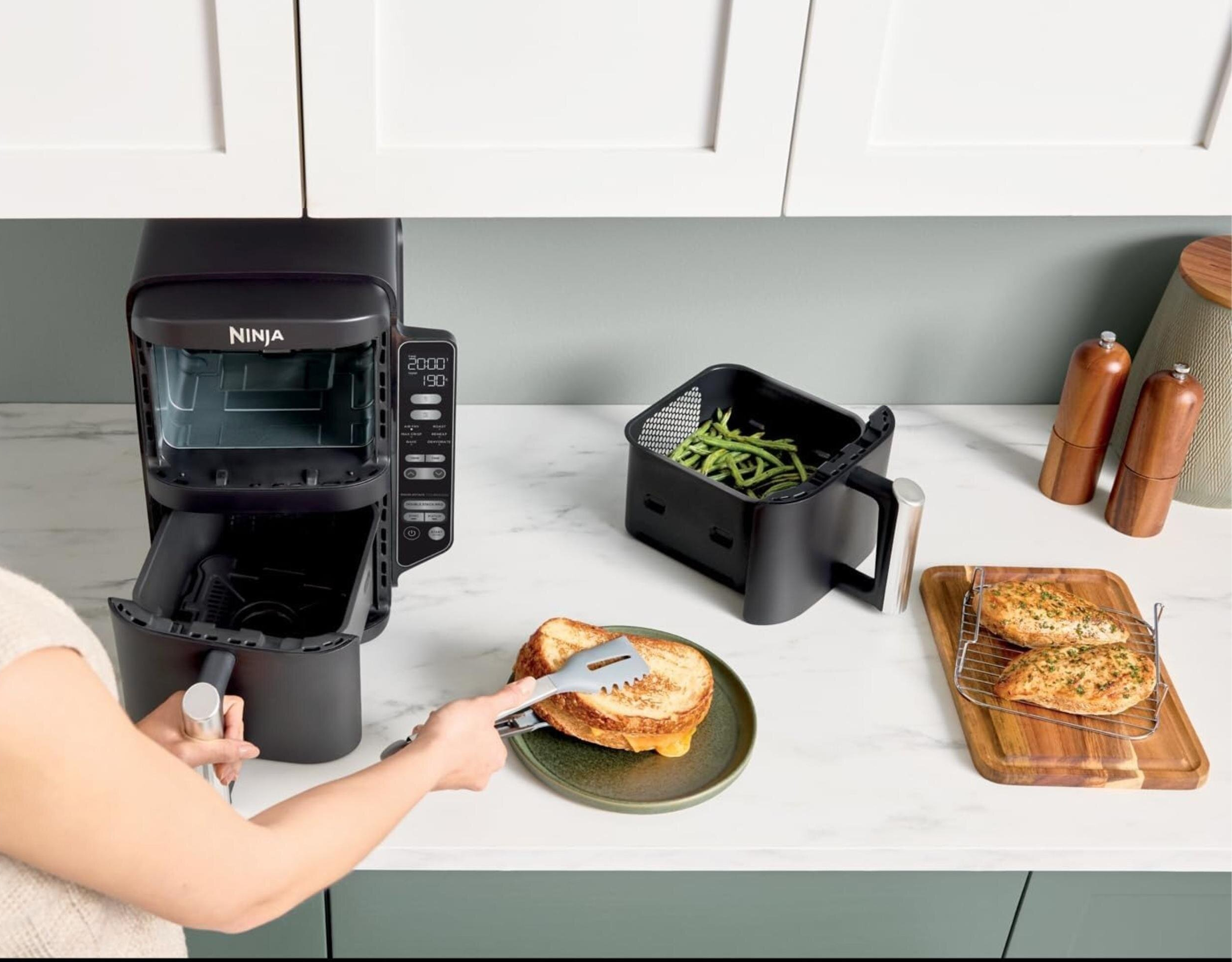 Frytownica beztłuszczowa z osobą używającą szczypiec do umieszczenia grillowanej kanapki z serem na talerzu.