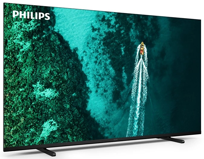 Duży telewizor Philips wyświetlający turkusową scenę oceanu z łodzią. Telewizor stoi na czarnych podstawkach.