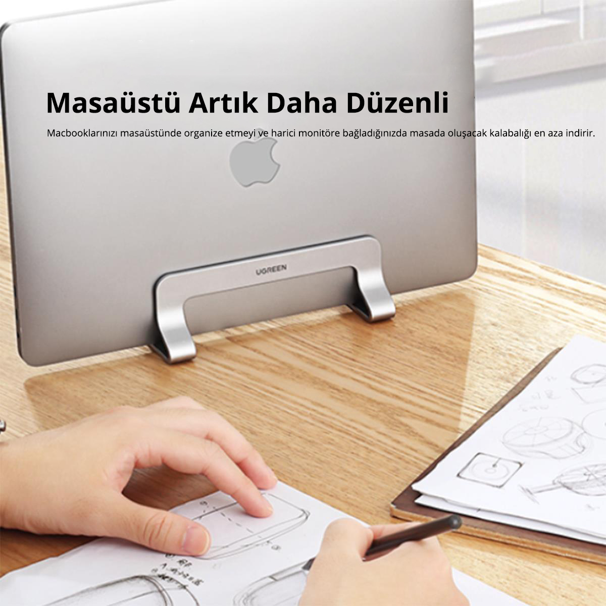 Masada standlı dizüstü bilgisayar, el kağıda çizim yapıyor, kutuda metin.