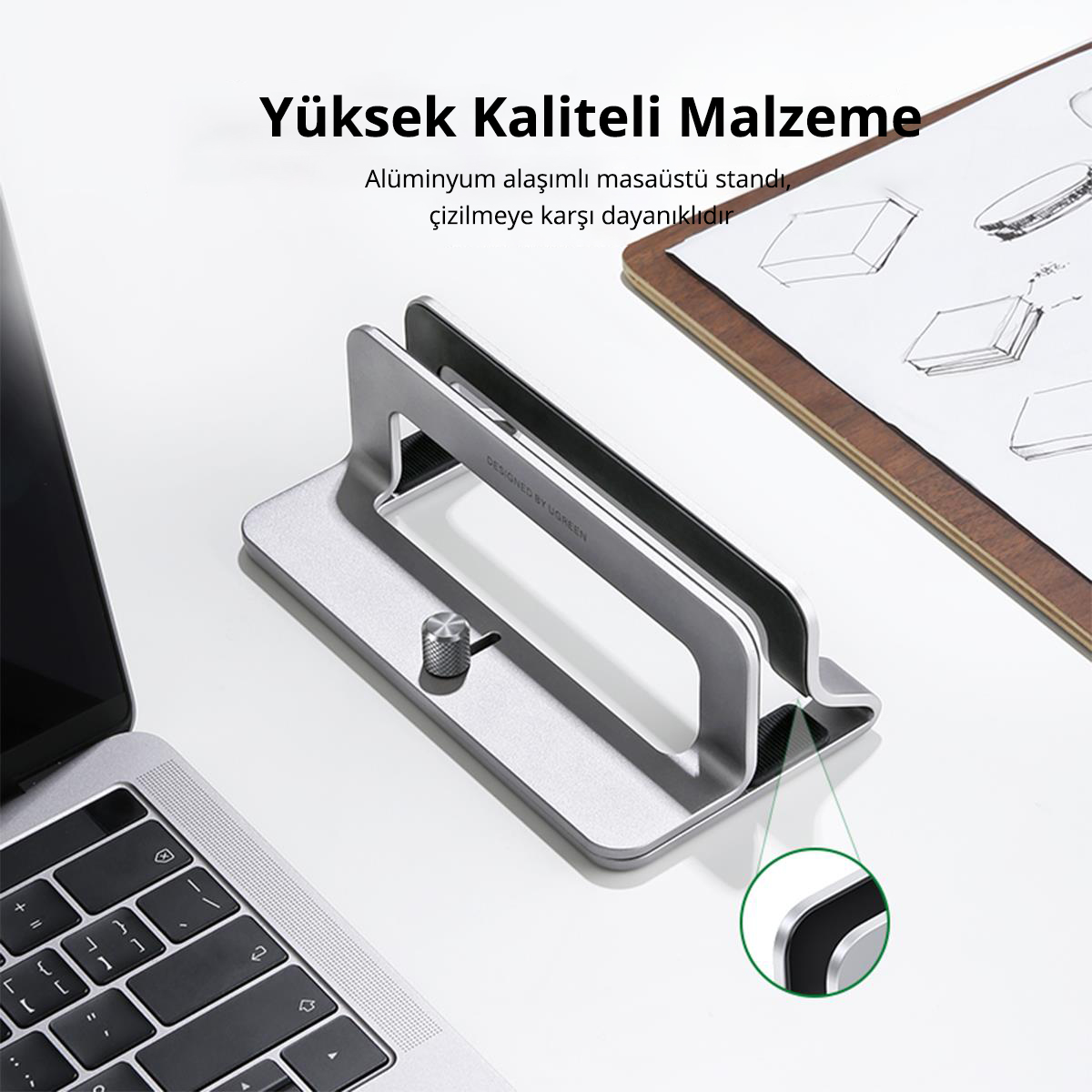 "Yüksek Kaliteli Malzeme" metniyle bir dizüstü bilgisayar ve not defteri ile gümüş dizüstü bilgisayar standı.