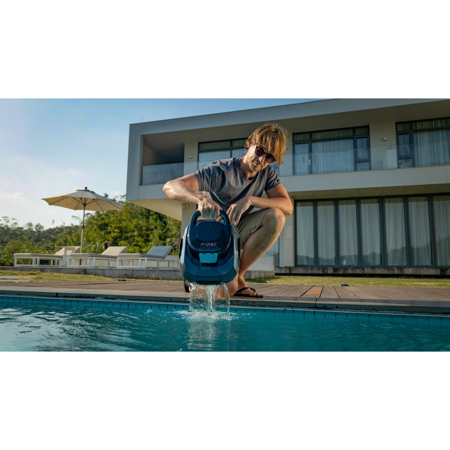 Un uomo tiene un robot di pulizia blu e lo lascia andare in piscina.