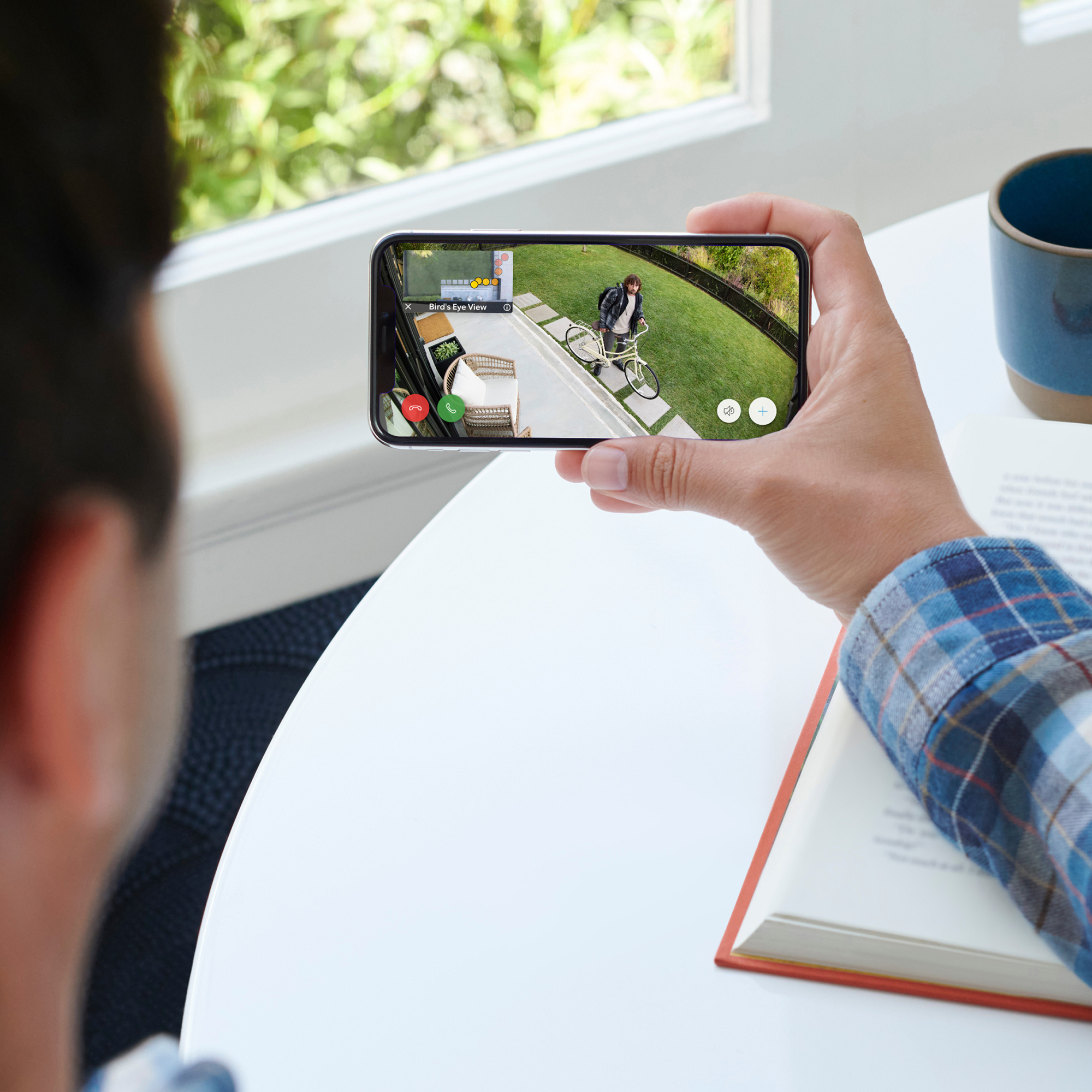 Person hält Telefon mit Ring-Video, in der Nähe eines Tisches.