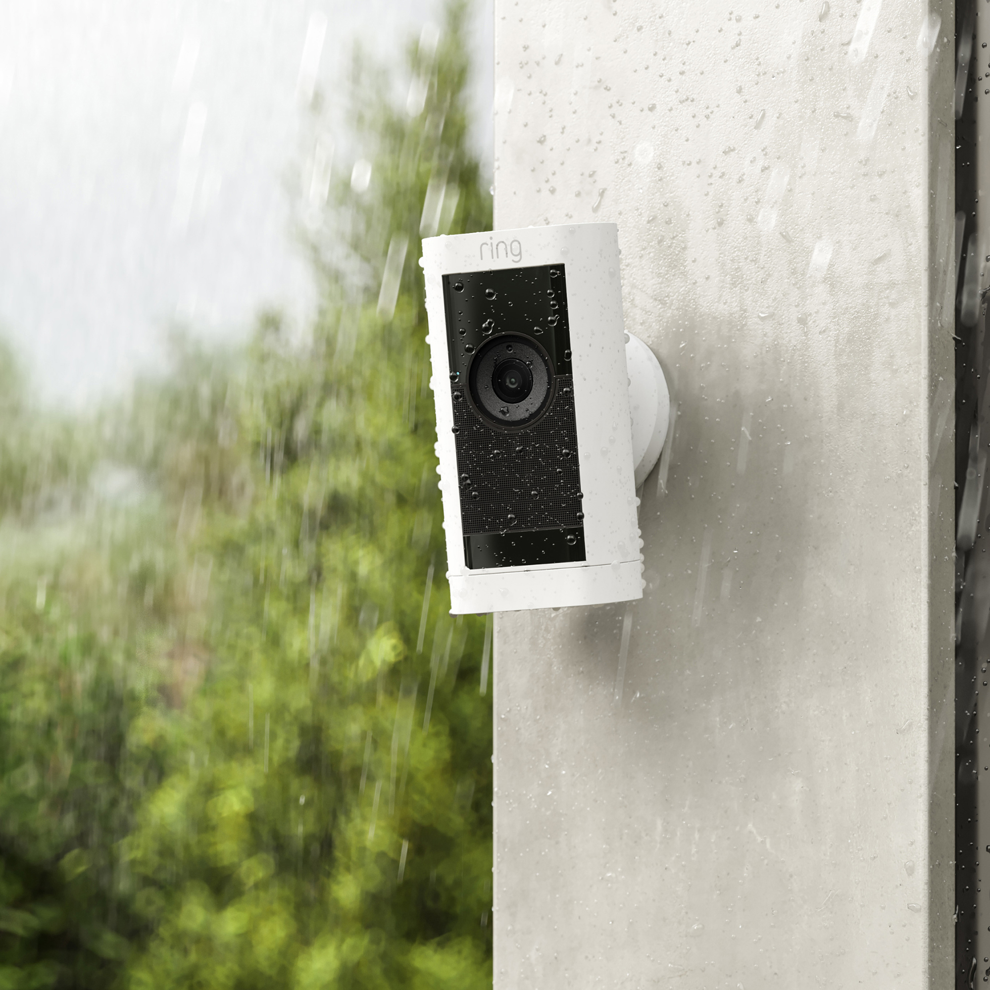 Weiße Überwachungskamera, montiert an einer Wand im Regen.