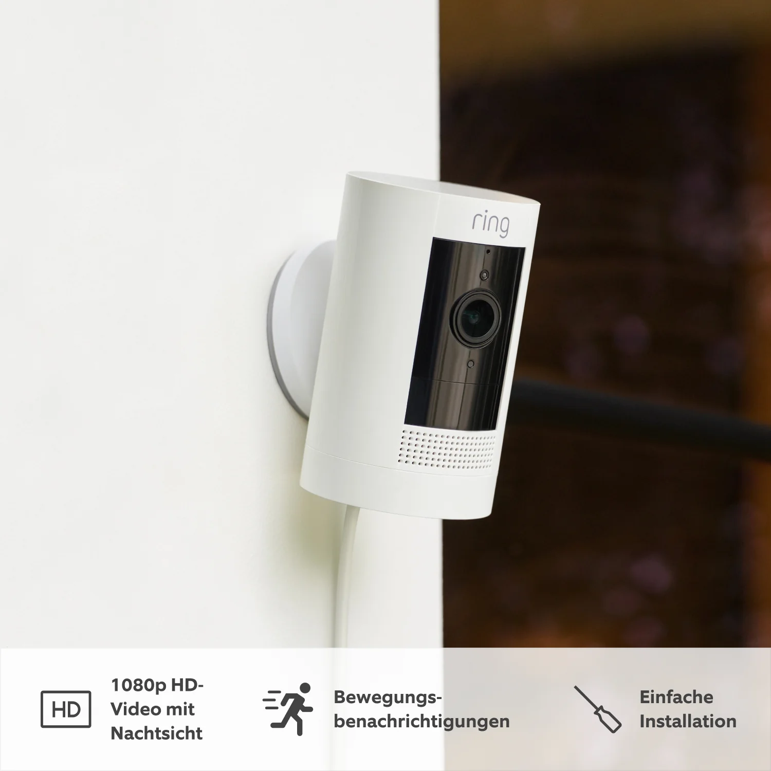 Eine weiße Ring-Überwachungskamera, die an einer weißen Wand montiert ist. Sie ist nach unten abgewinkelt.