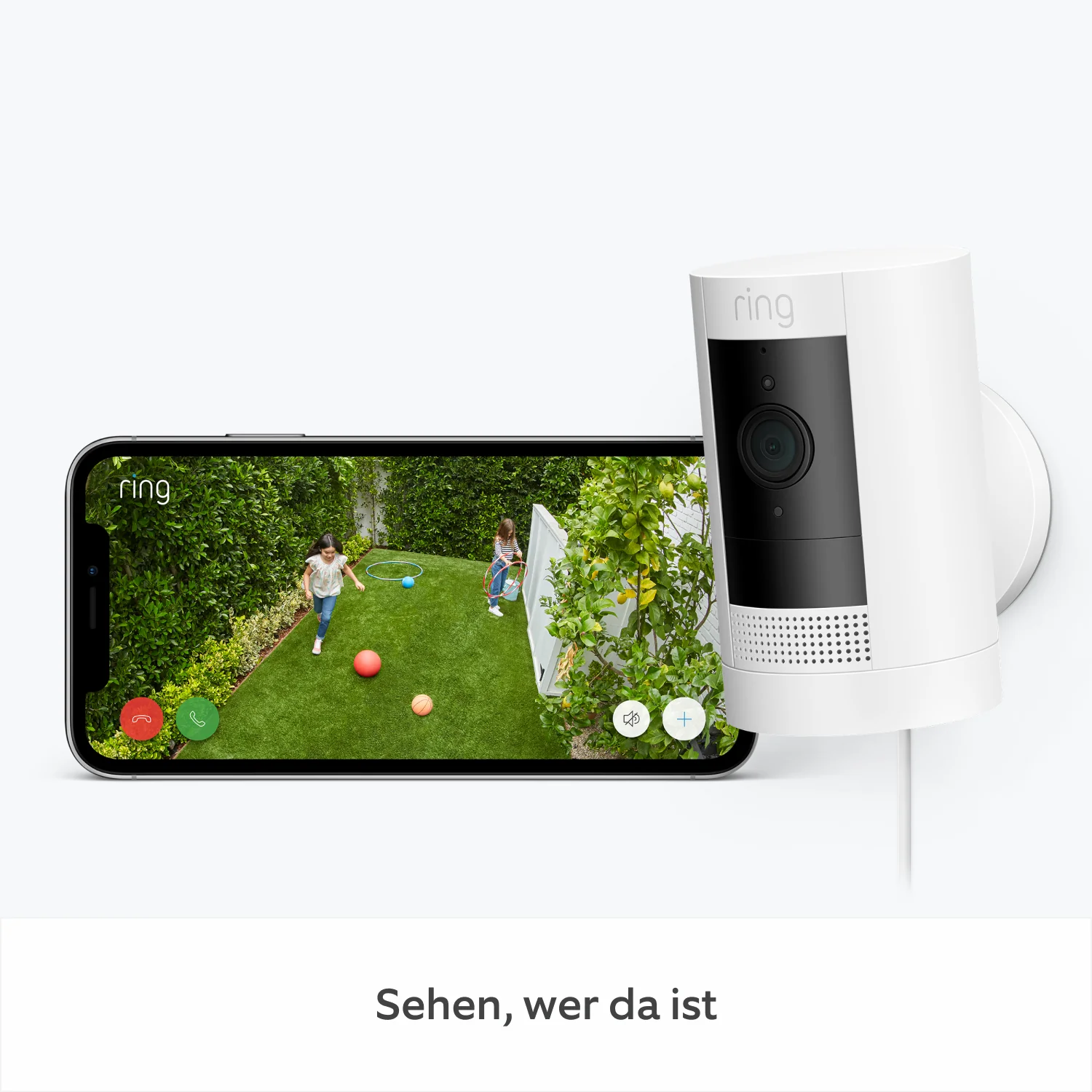 Eine weiße Überwachungskamera an einer Wand, die eine Live-Ansicht auf einem Telefon von Kindern zeigt, die in einem Hof spielen.