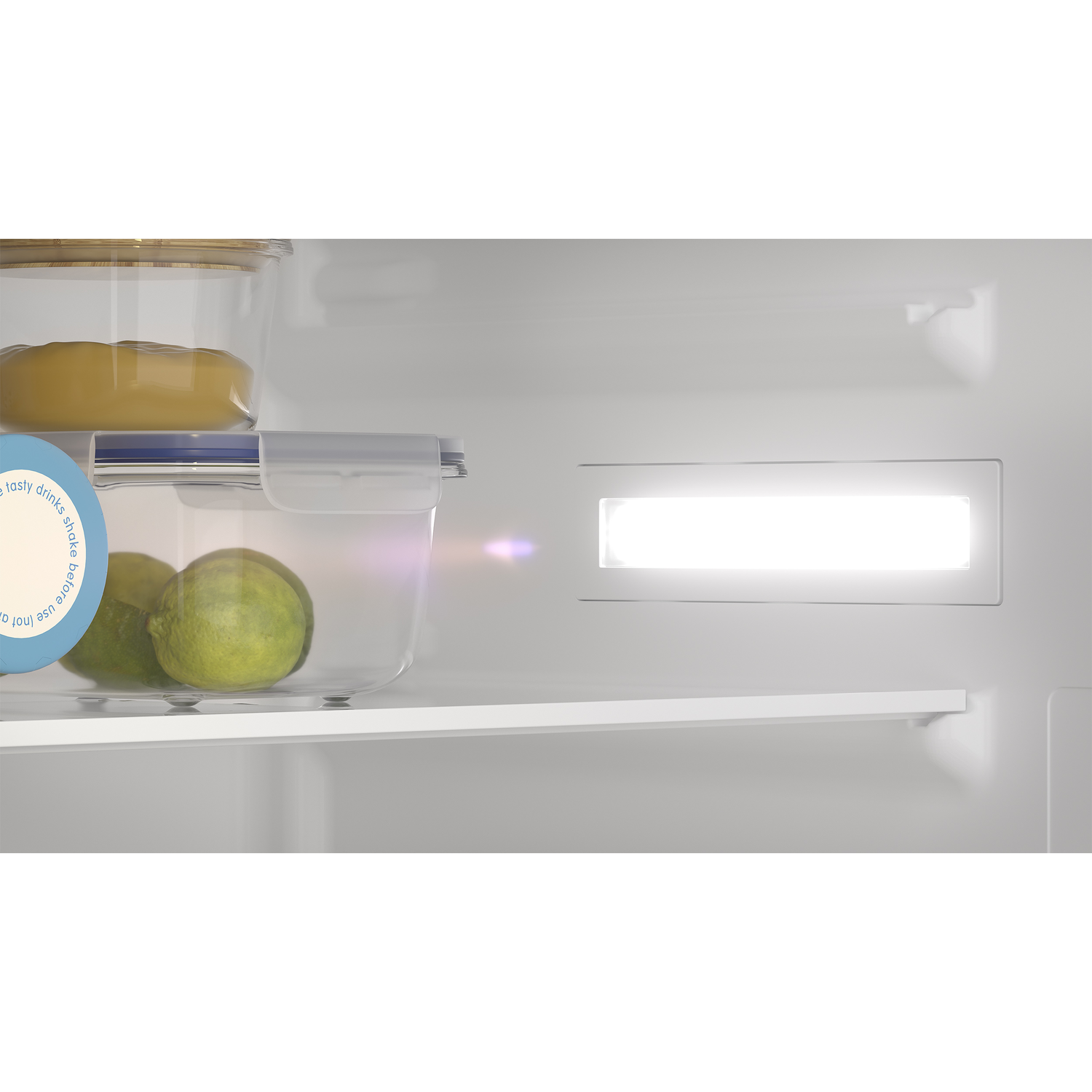 Inside a refrigerator, visible are clear containers with food and a bright light.