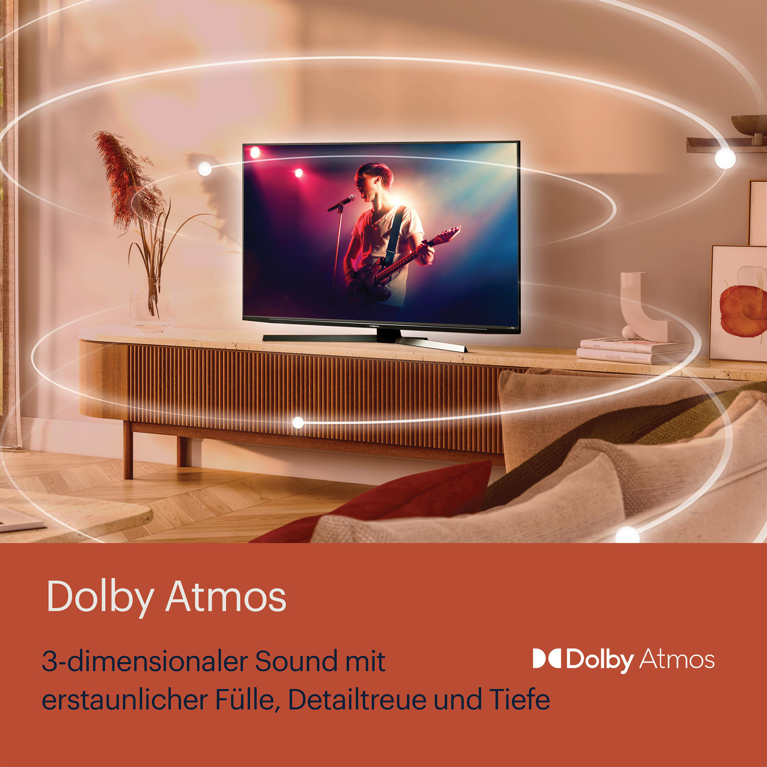Ein Mann spielt Gitarre auf der Bühne, dargestellt auf einem Fernseher mit Text über Dolby Atmos.