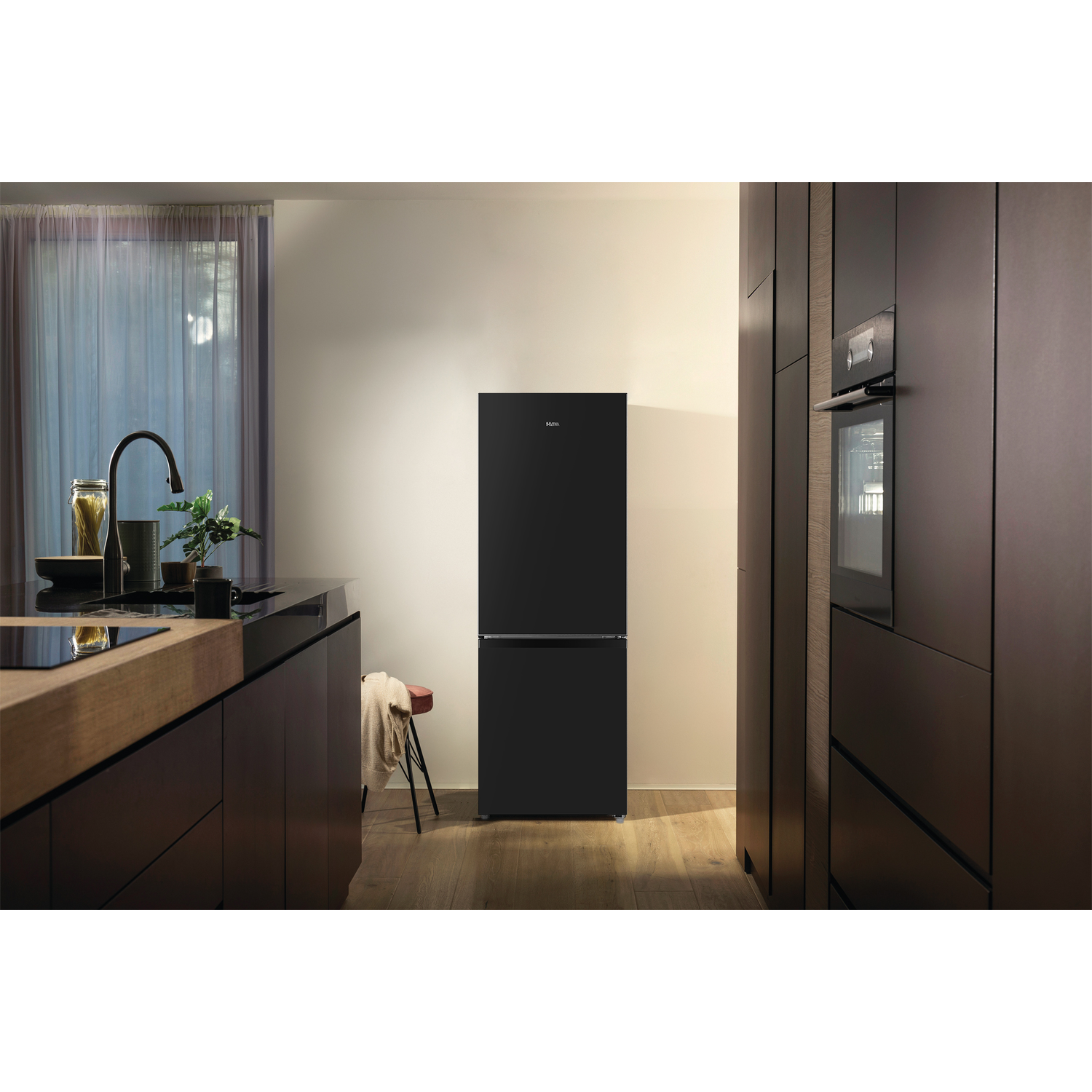 A black fridge in a kitchen setting. It stands between dark cabinets.