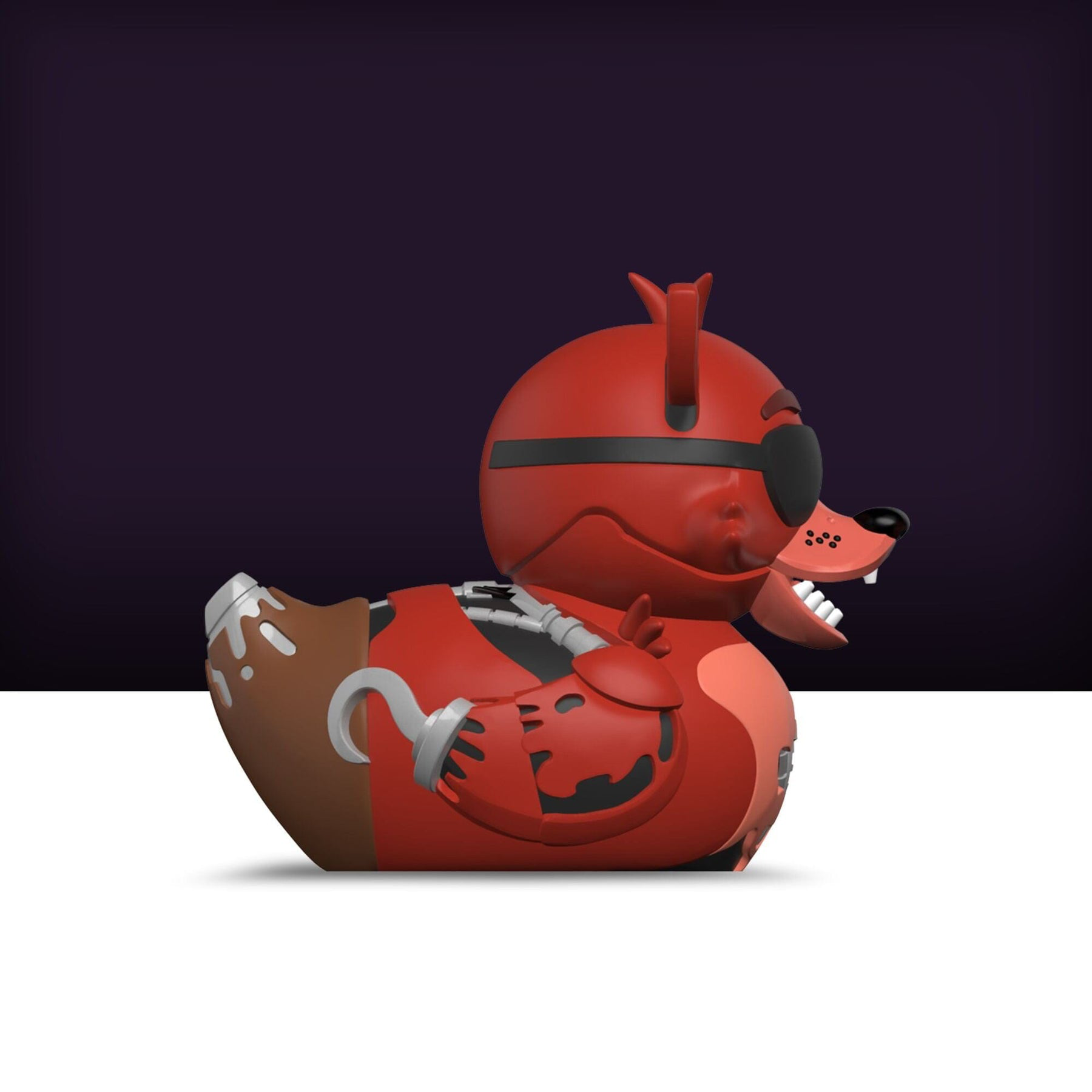 Piros Foxy gumikacsa szemkötővel és robotkarral. Sötét lila és fehér háttér.