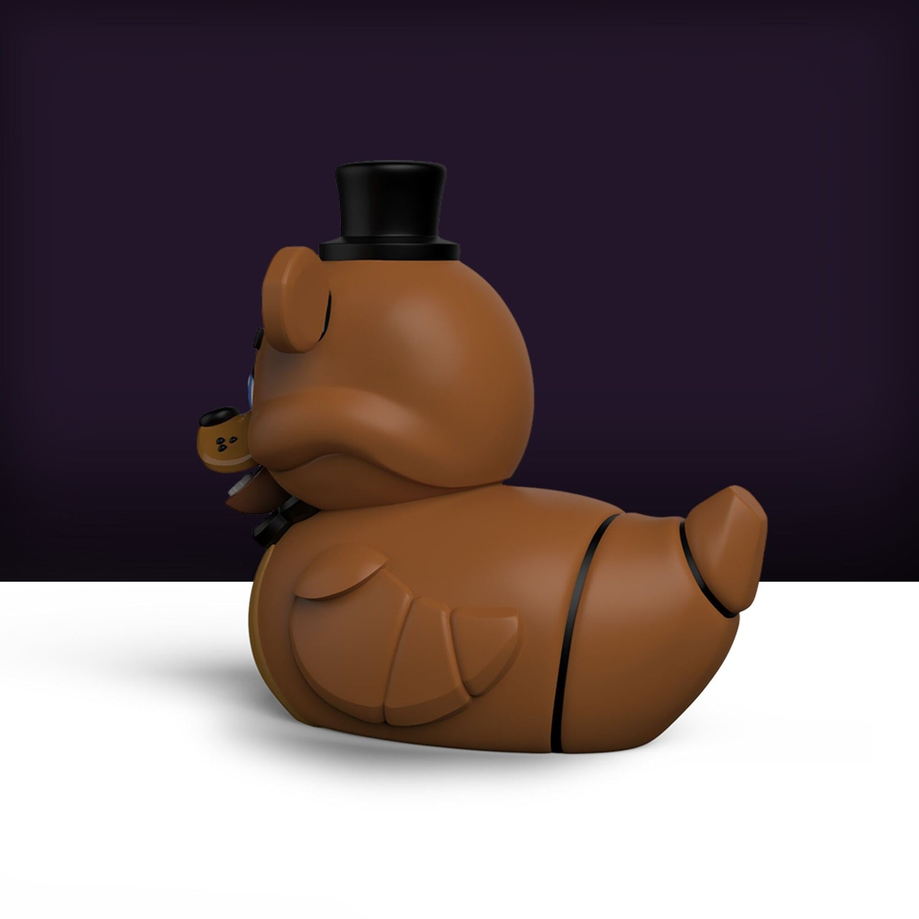 Barna Freddy Fazbear gumikacsa. Fekete cilinder és csokornyakkendő. Sötét lila és fehér háttér.