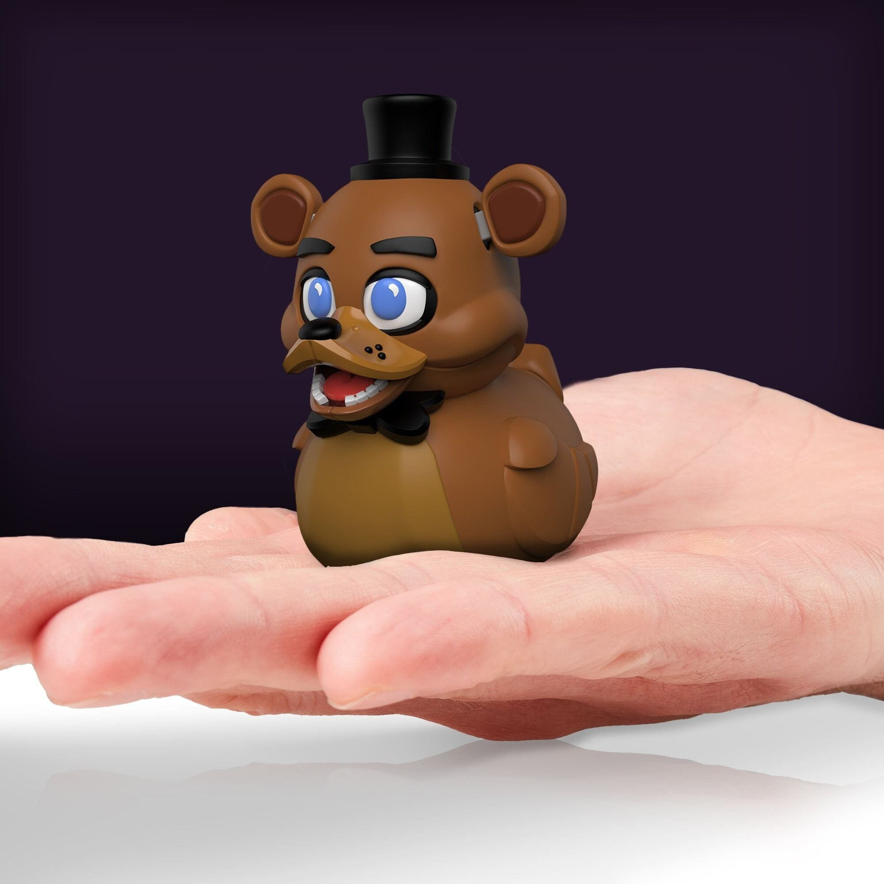 Egy Freddy Fazbear játékfigura egy kézben, lila háttérrel.