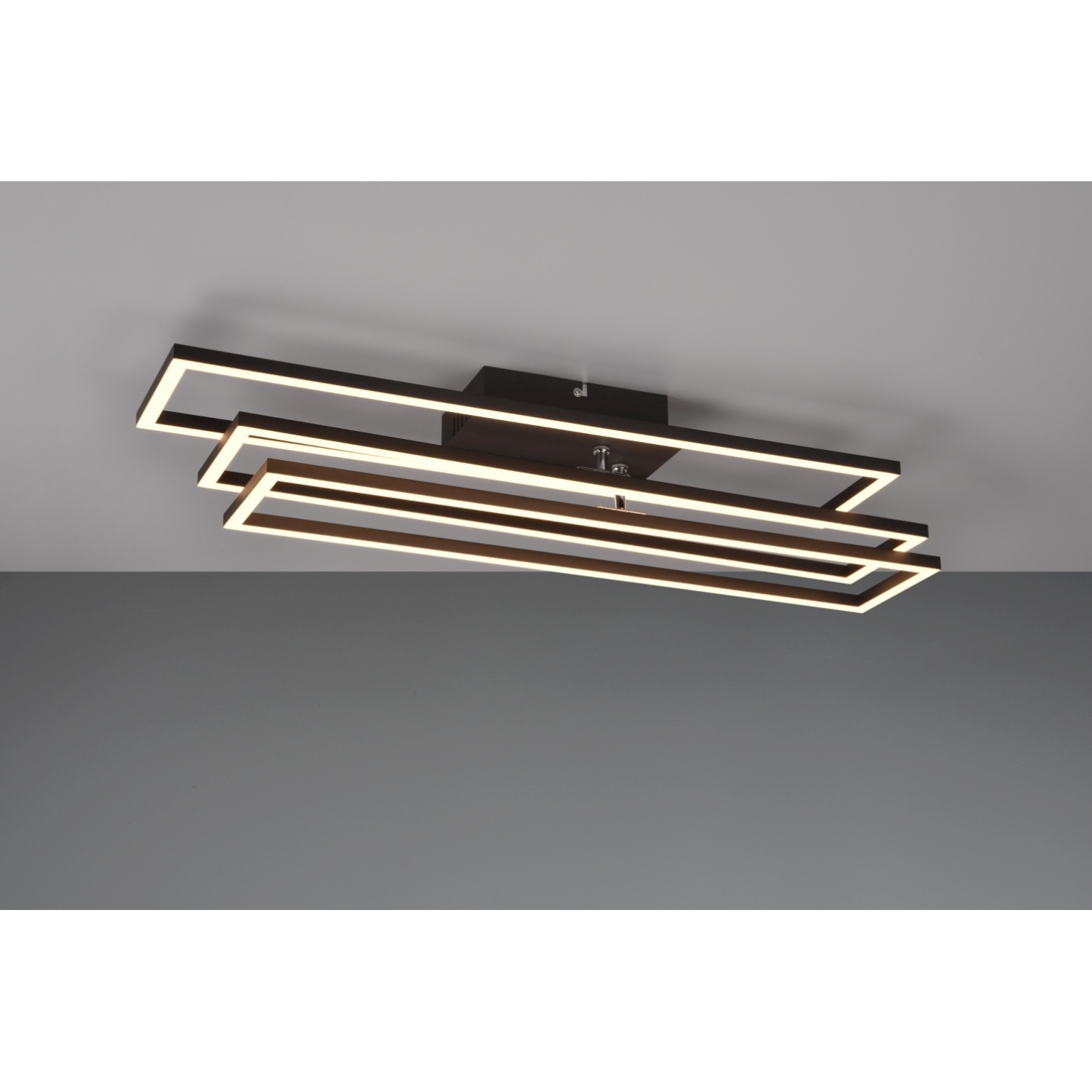 Lampada da soffitto moderna con tre cornici rettangolari. La luce è marrone scuro, lo sfondo è grigio.