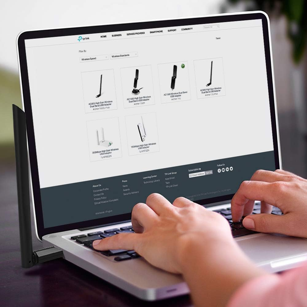 Ein Laptop zeigt eine Website mit drahtlosen Adaptern. Hände tippen auf der Tastatur.