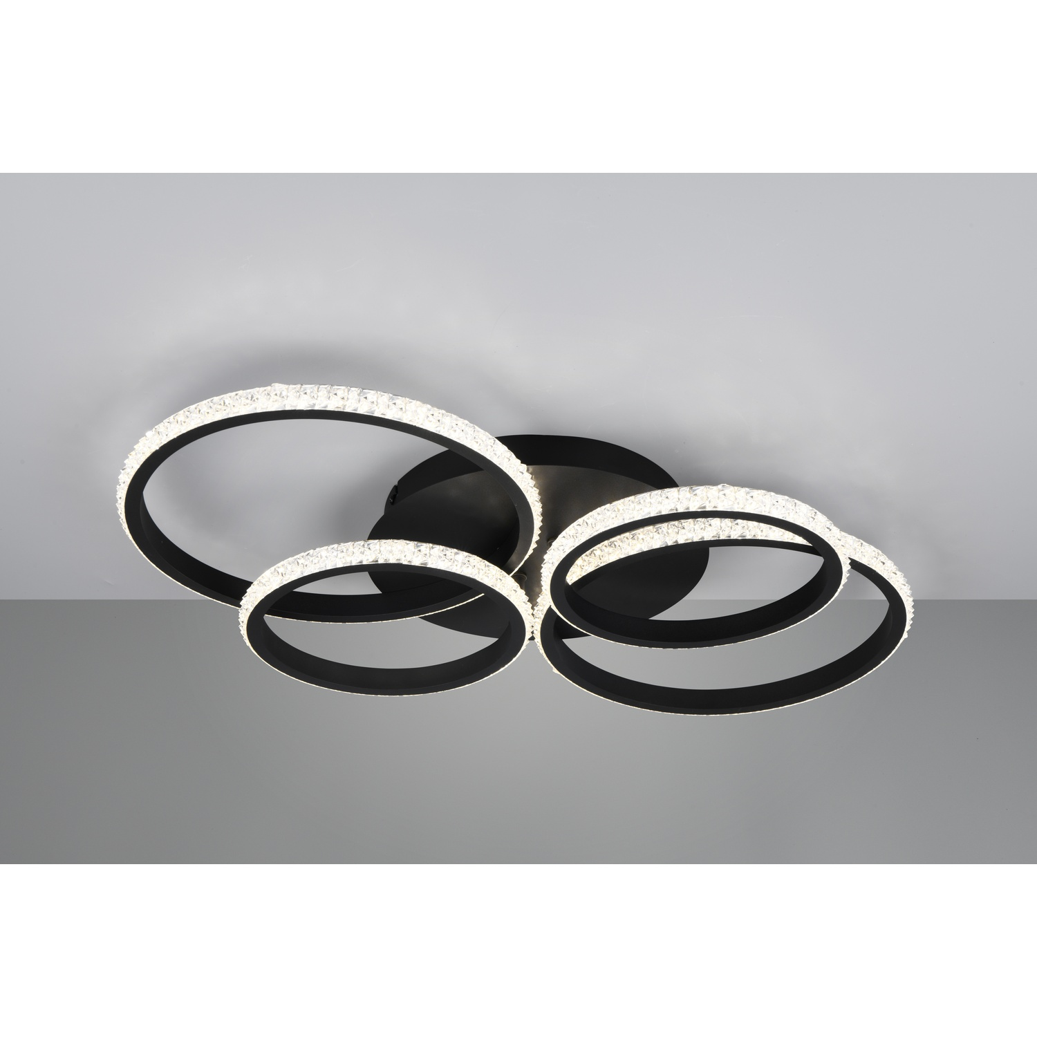 Lampada da soffitto con quattro anelli luminosi circolari interconnessi, bianco e nero.