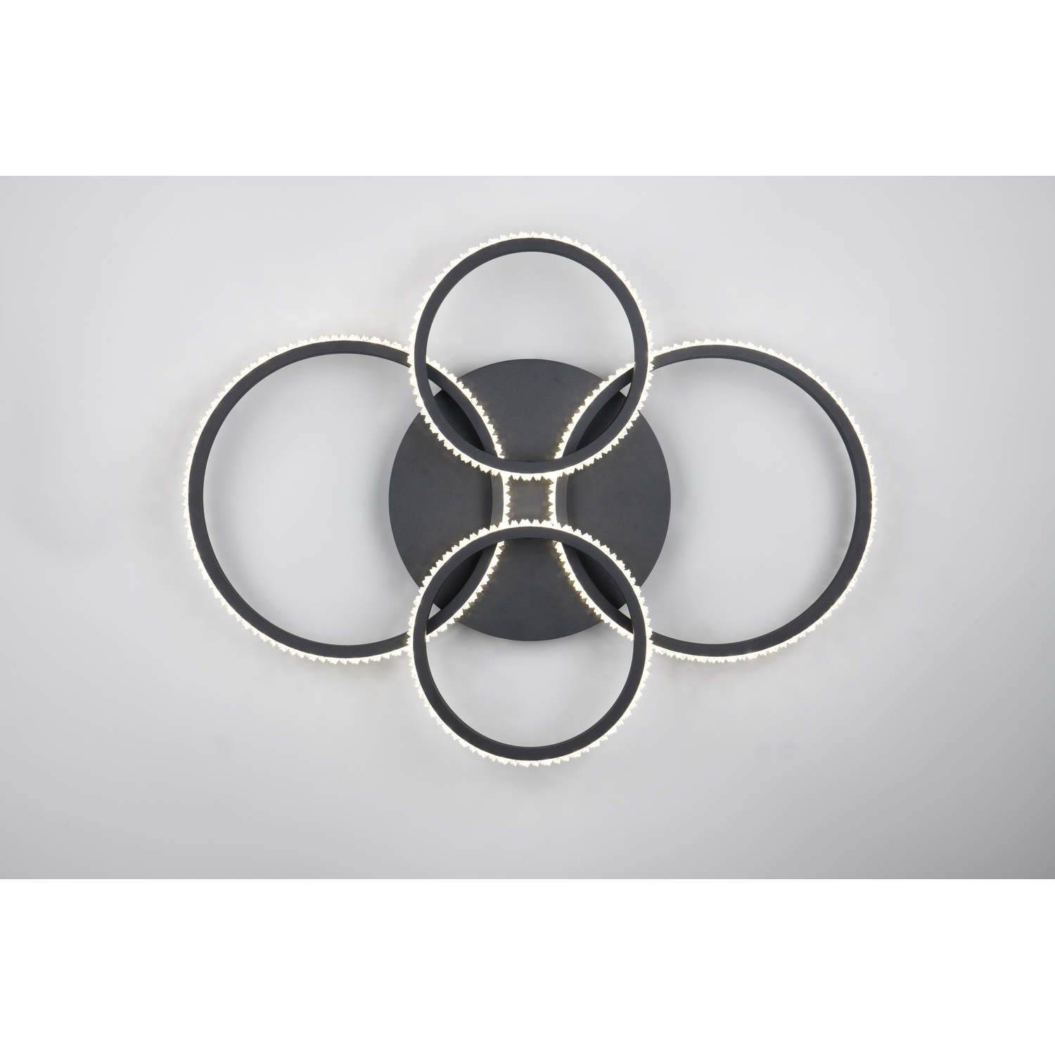 Apparecchio di illuminazione a soffitto moderno. È nero, con quattro anelli di luce circolari e una base centrale.