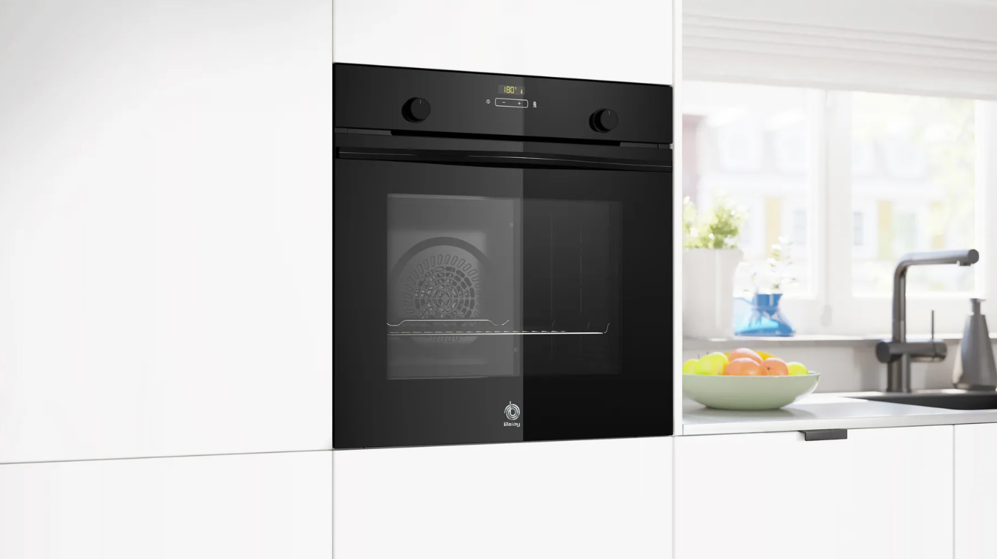 Horno empotrado negro en cocina blanca, frutero en encimera.