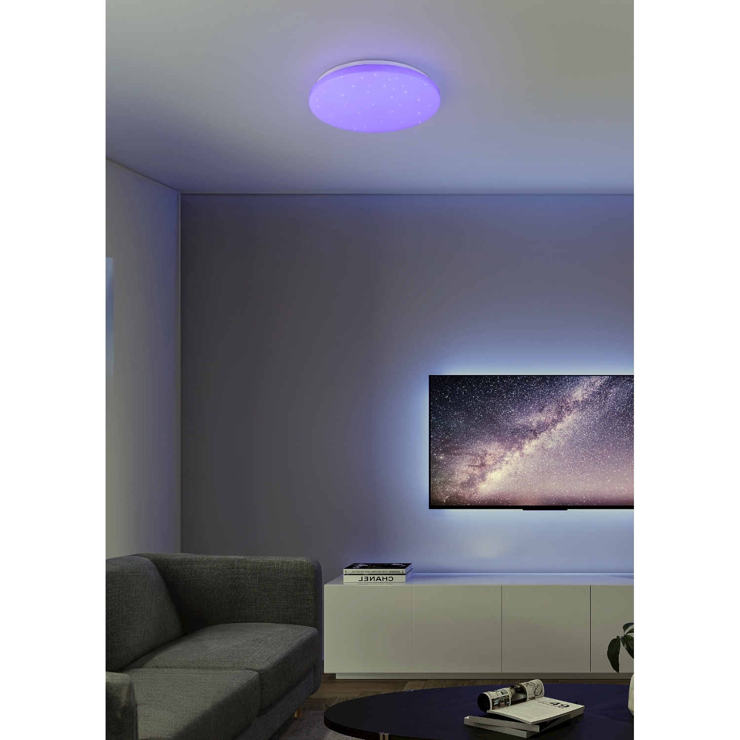 Una stanza con una luce a soffitto viola e una TV.