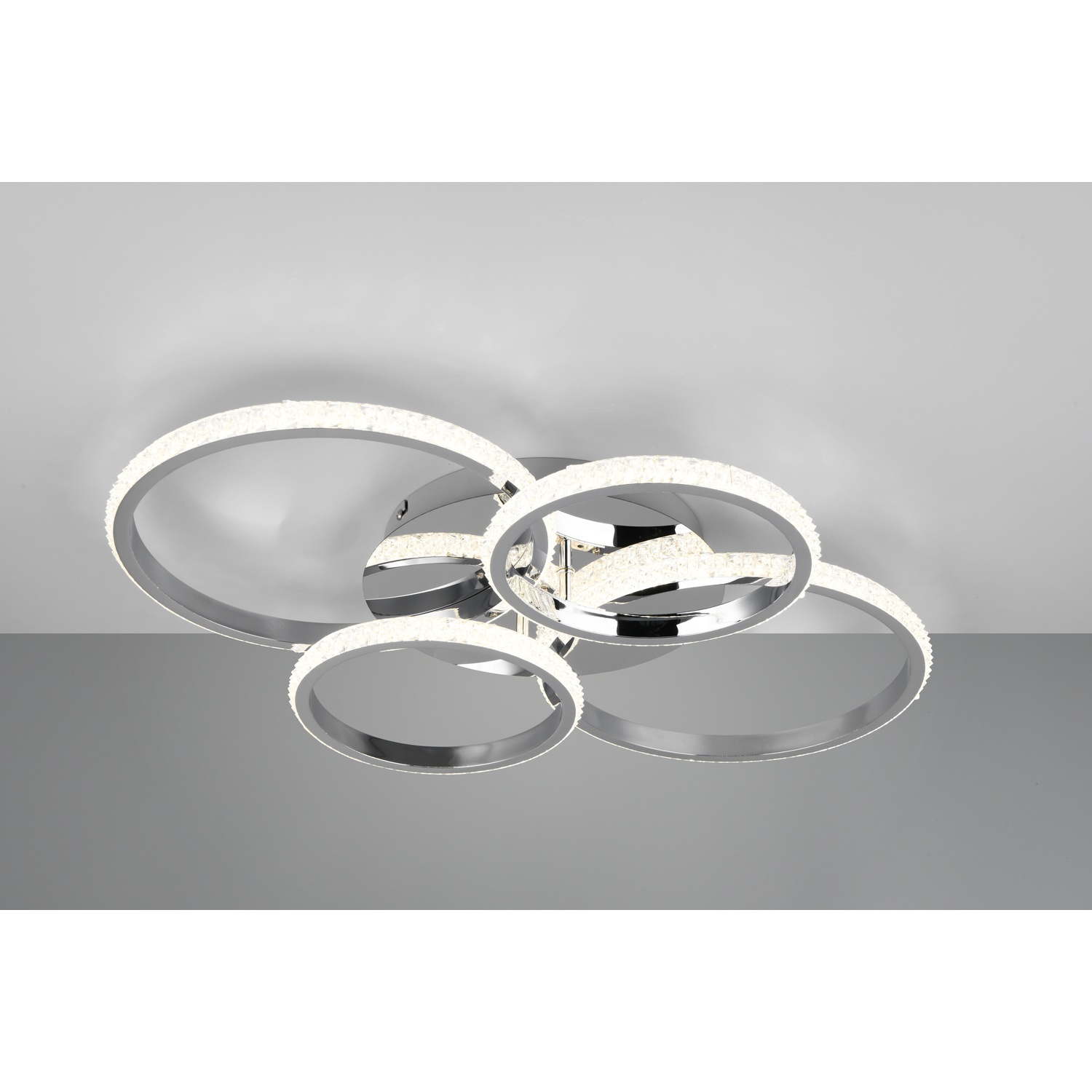 Un lampadario a soffitto con quattro anelli argentati e decorazioni simili a cristalli, soffitto bianco.
