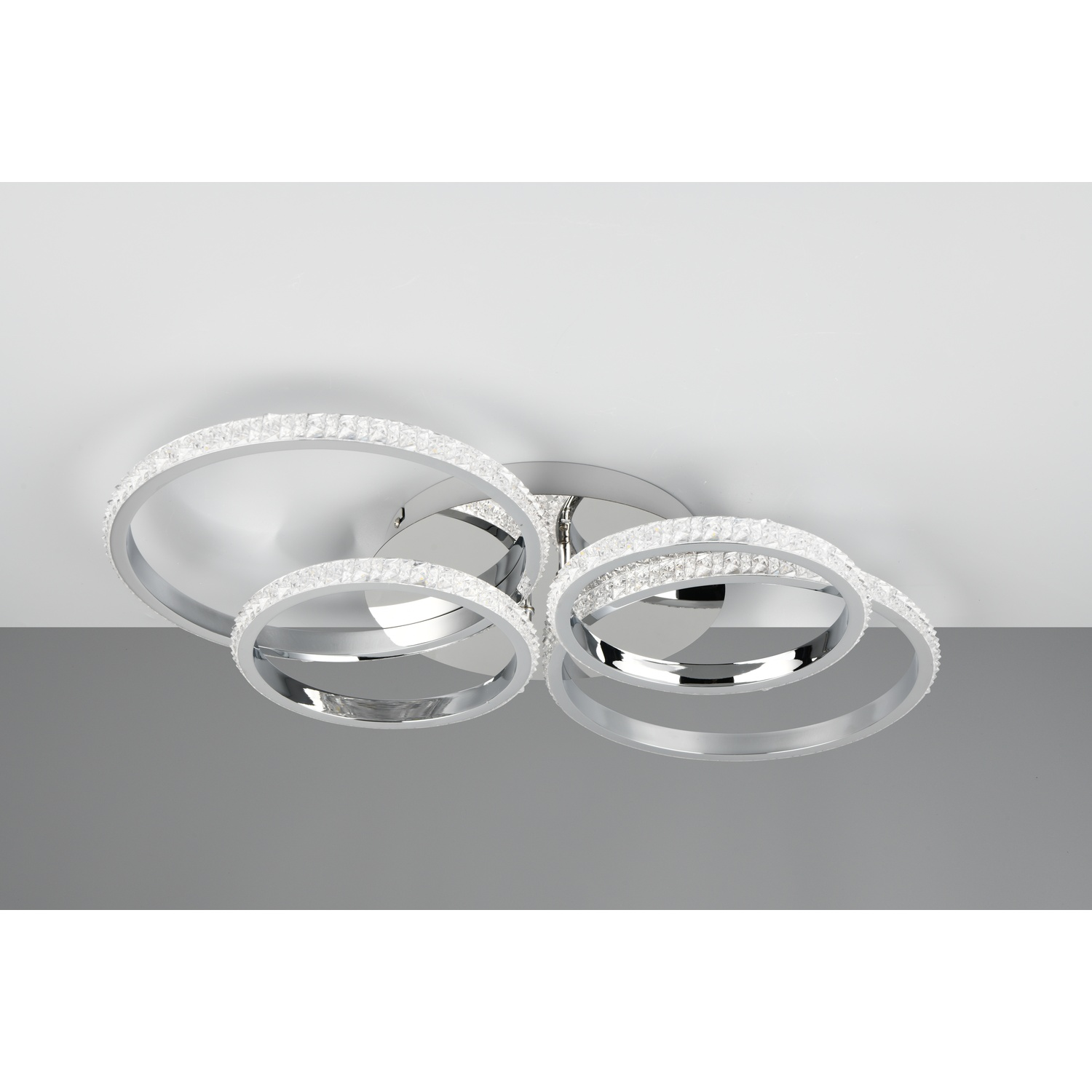 Apparecchio di illuminazione a soffitto con quattro anelli argentati, incastonati con cristalli, finitura cromata, su sfondo bianco.