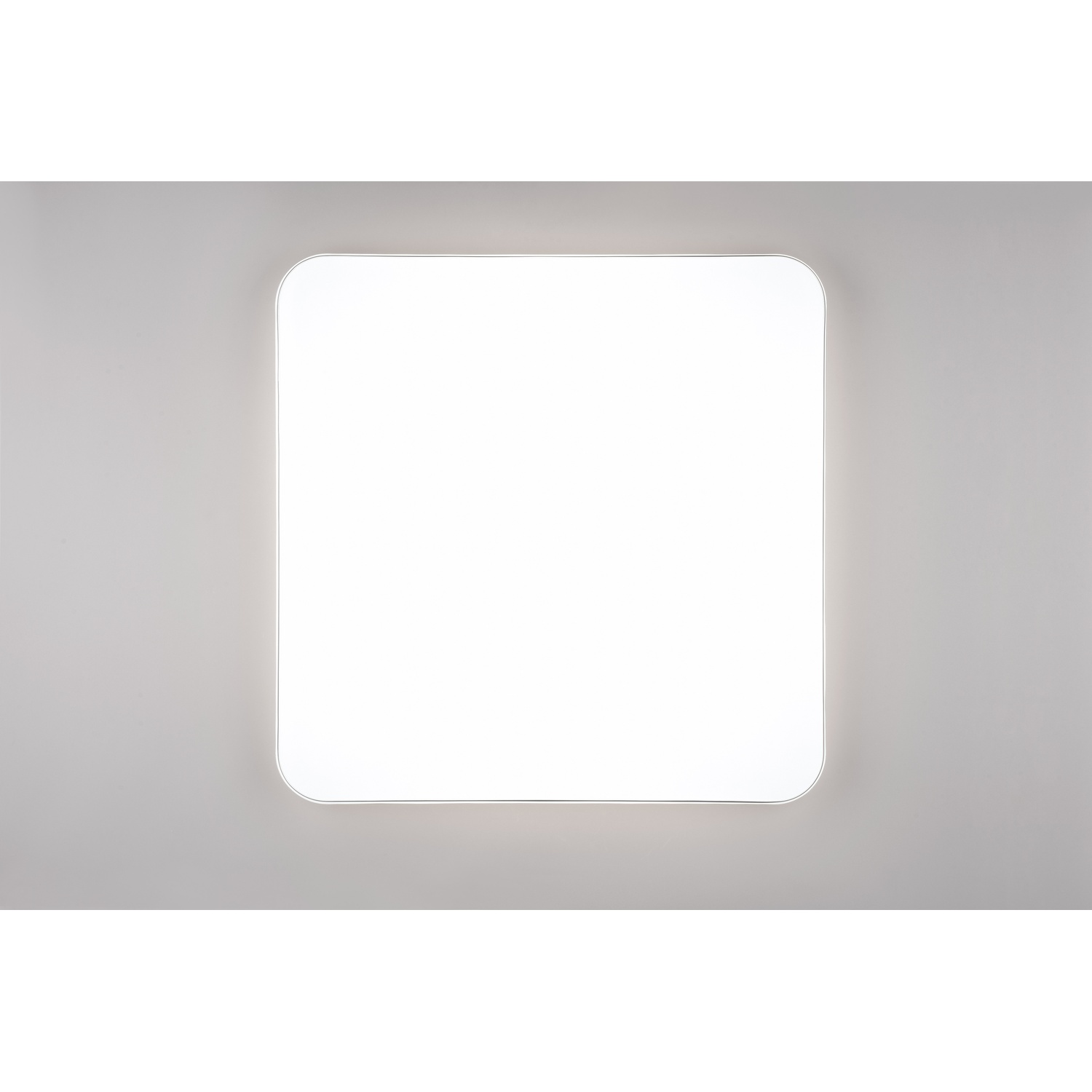 Un apparecchio di illuminazione a LED bianco quadrato. L'apparecchio è montato su una parete grigia.
