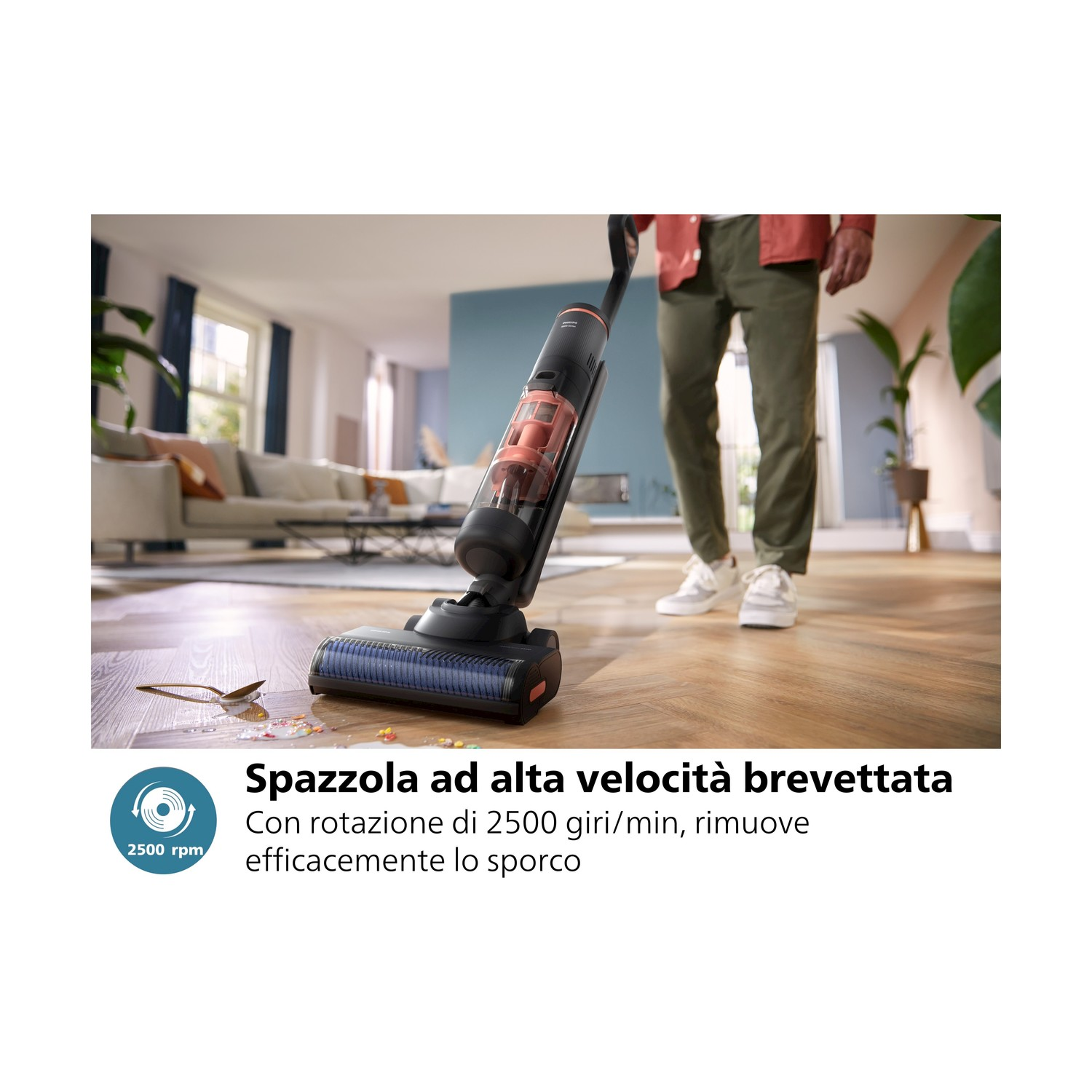 Una persona usa un aspirapolvere su un pavimento in legno, vicino a un divano e una pianta.