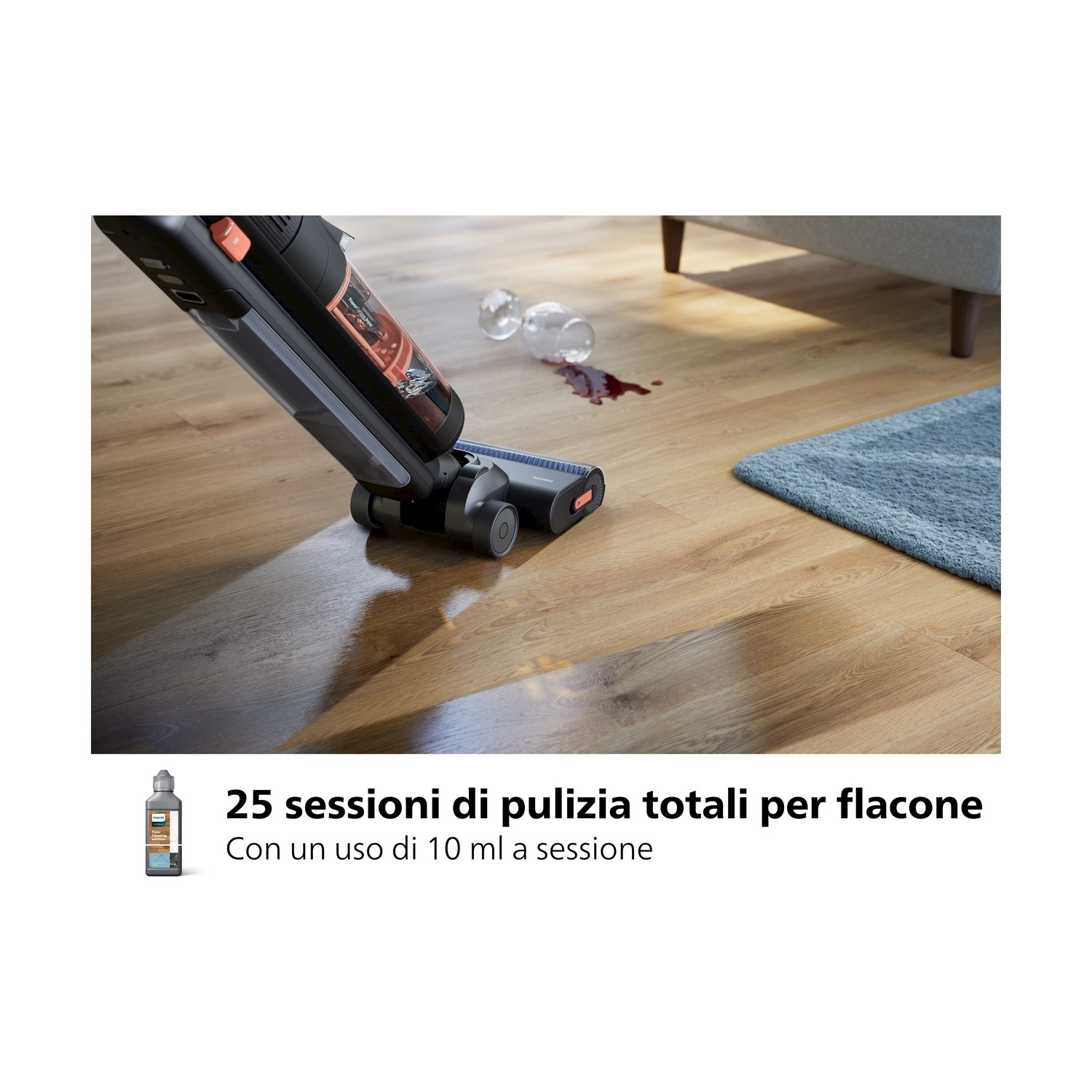 Un aspirapolvere pulisce un pavimento in legno con liquido versato e bicchieri rotti.