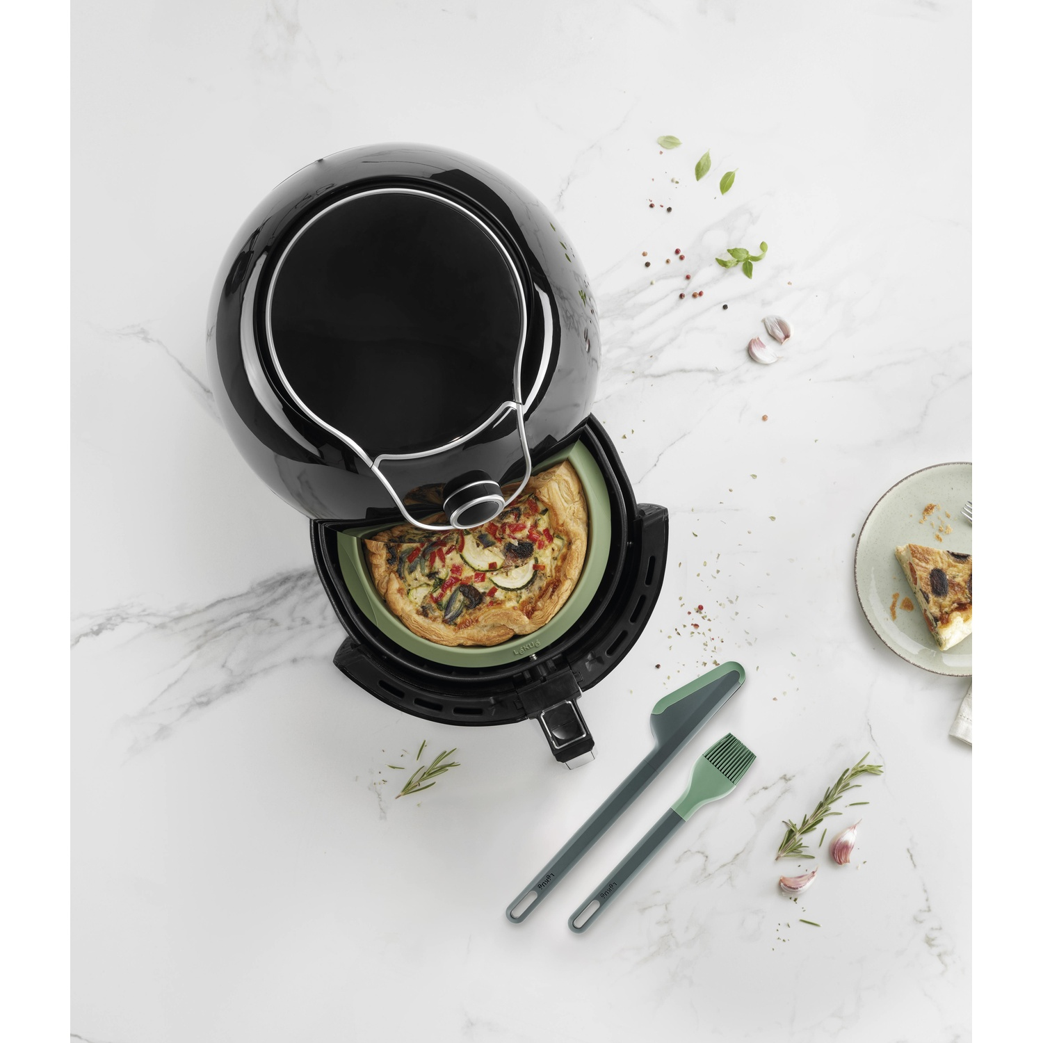 Een airfryer met een pizza erin. De airfryer is zwart en staat op een marmeren oppervlak.