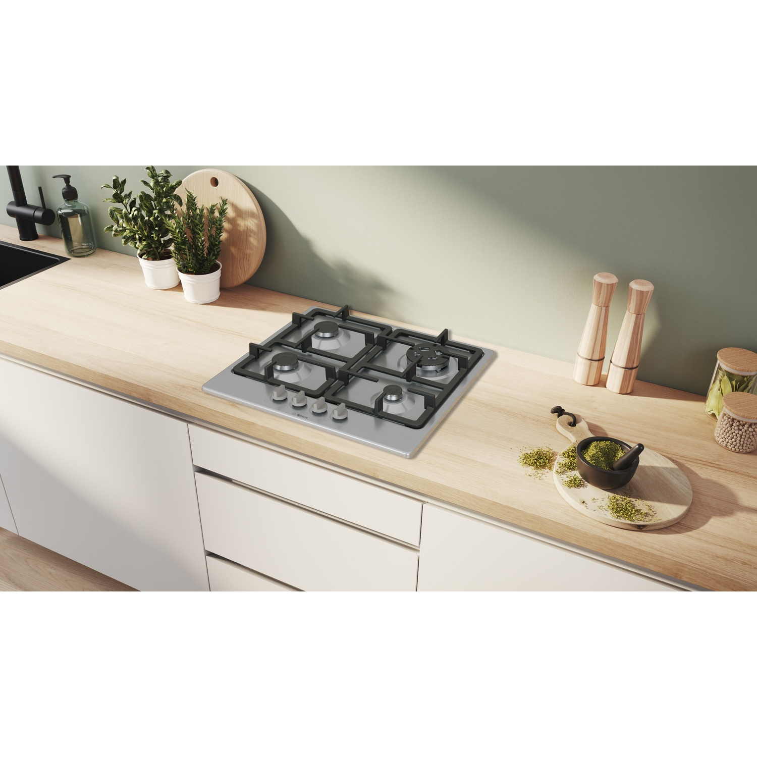 Un piano cottura a gas integrato in acciaio inossidabile su un ripiano in legno chiaro in una cucina.