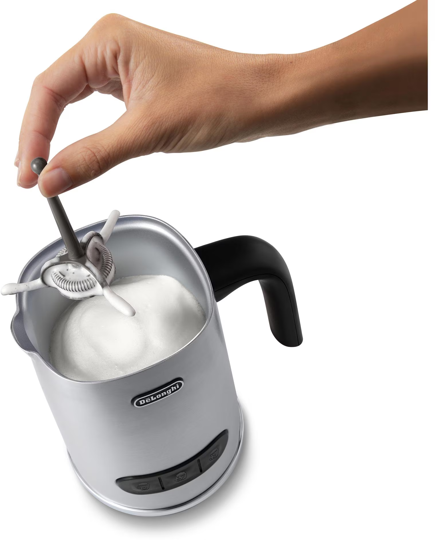 Mano che monta il latte in una brocca di metallo con un montalatte manuale. Sfondo bianco.
