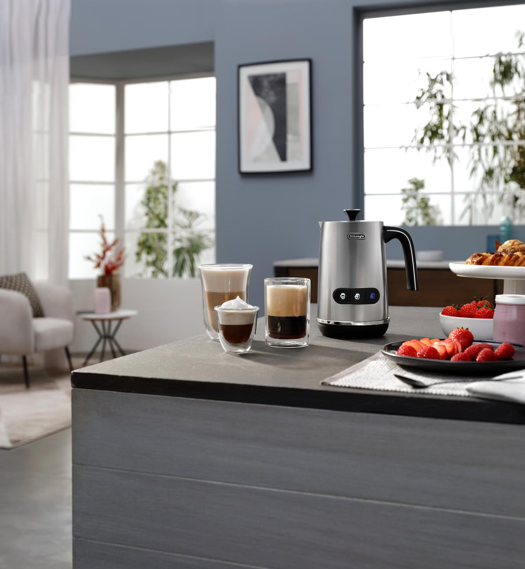Scena del bancone della cucina. Montalatte, bicchieri con caffè, fragole e una cornice.