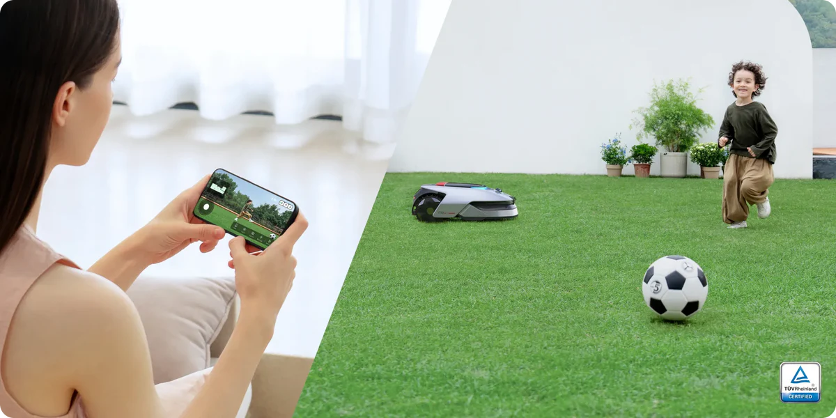 Frau mit Handy zeigt Rasenmäher-Steuerbildschirm. Kind rennt auf Gras neben Fußball und Roboter-Rasenmäher.