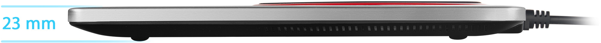Ezüst-fekete elektromos főzőlap oldalsó nézete. A magassága 23 mm. Hálózati kábel csatlakoztatva.