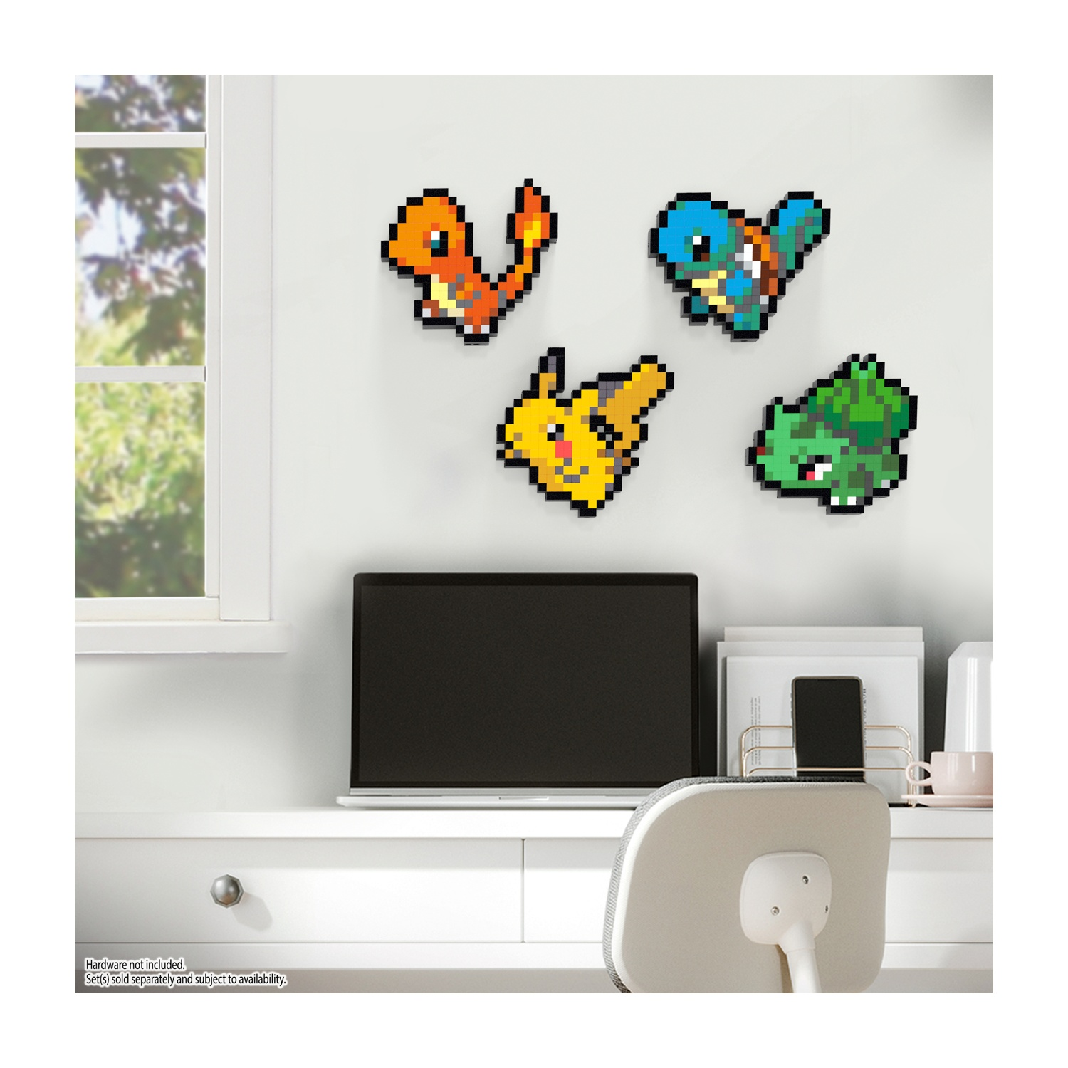 Quattro figure pixel art di Pokémon su un muro bianco. Un laptop nero è sotto.