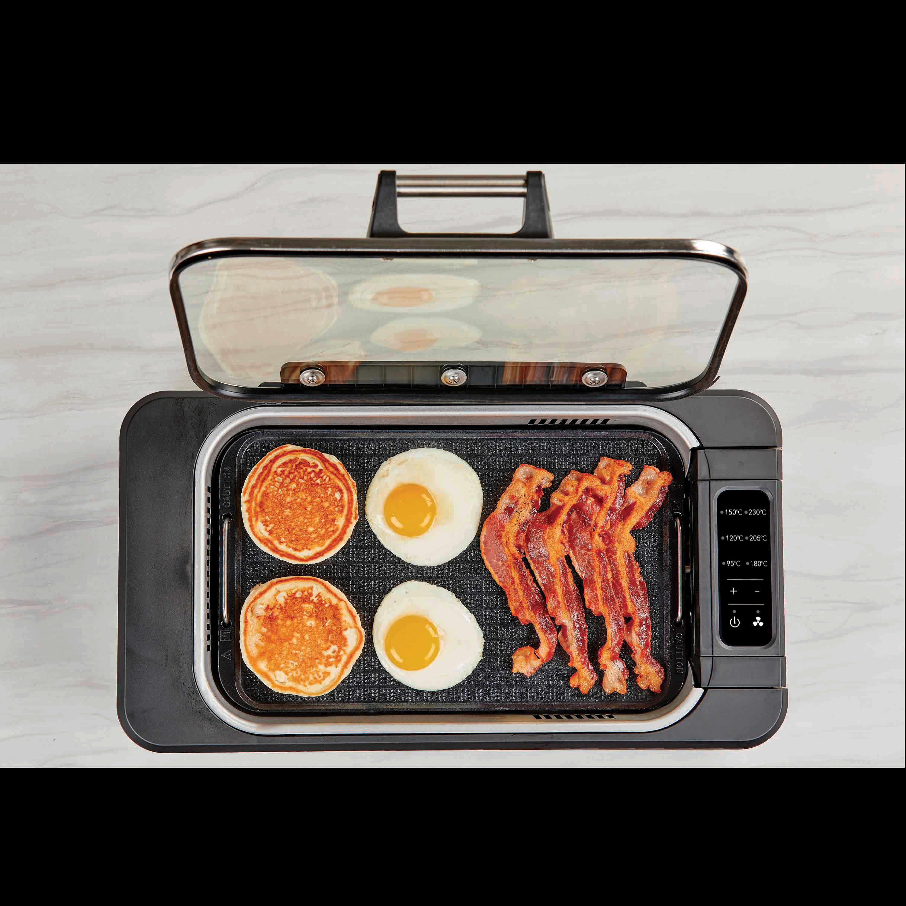Grillplatte, die Pfannkuchen, Eier und Speck zubereitet. Der Deckel ist offen.