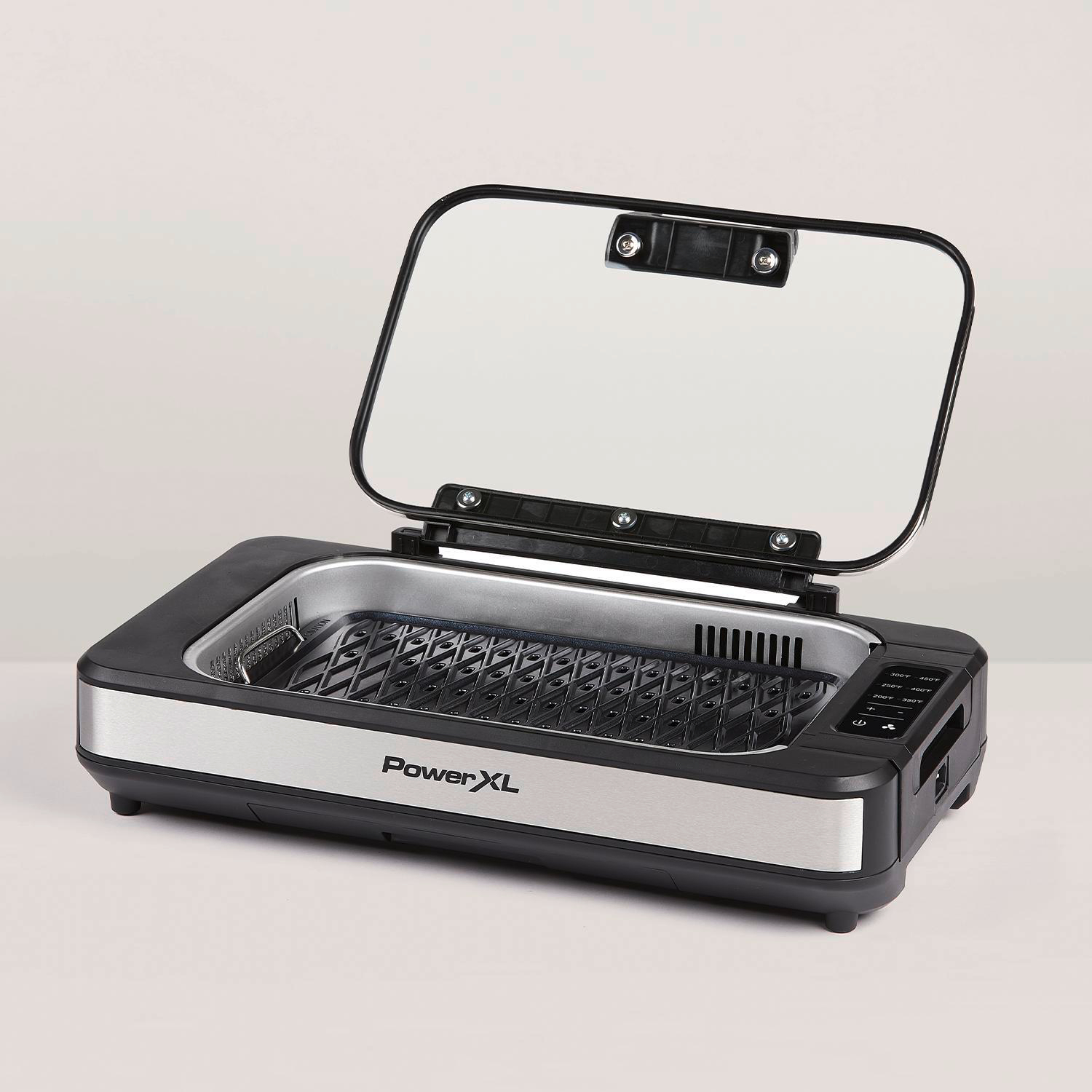 Ein elektrischer Grill mit Glasdeckel, silber und schwarz, auf weißem Grund.