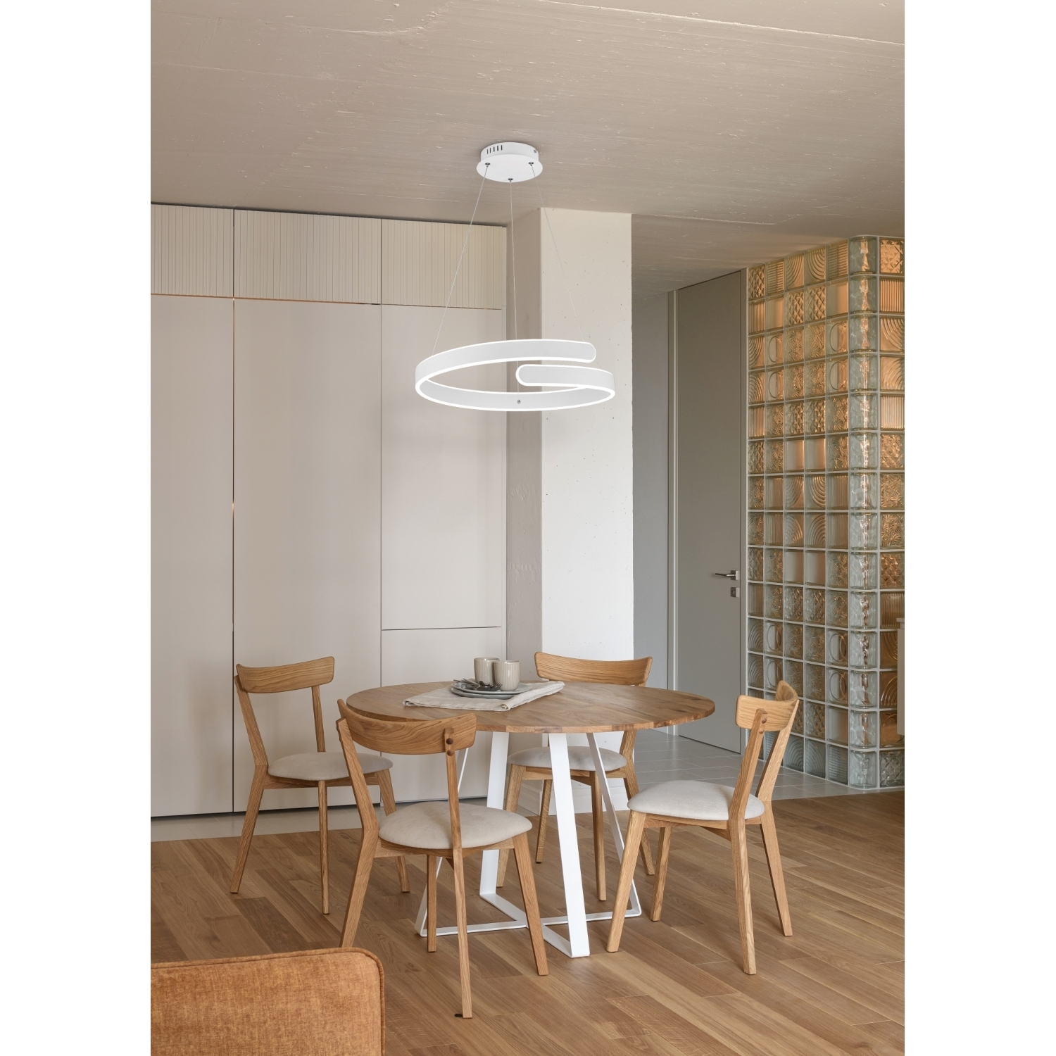 Sala da pranzo con tavolo rotondo e sedie. Un lampadario moderno è appeso sopra.