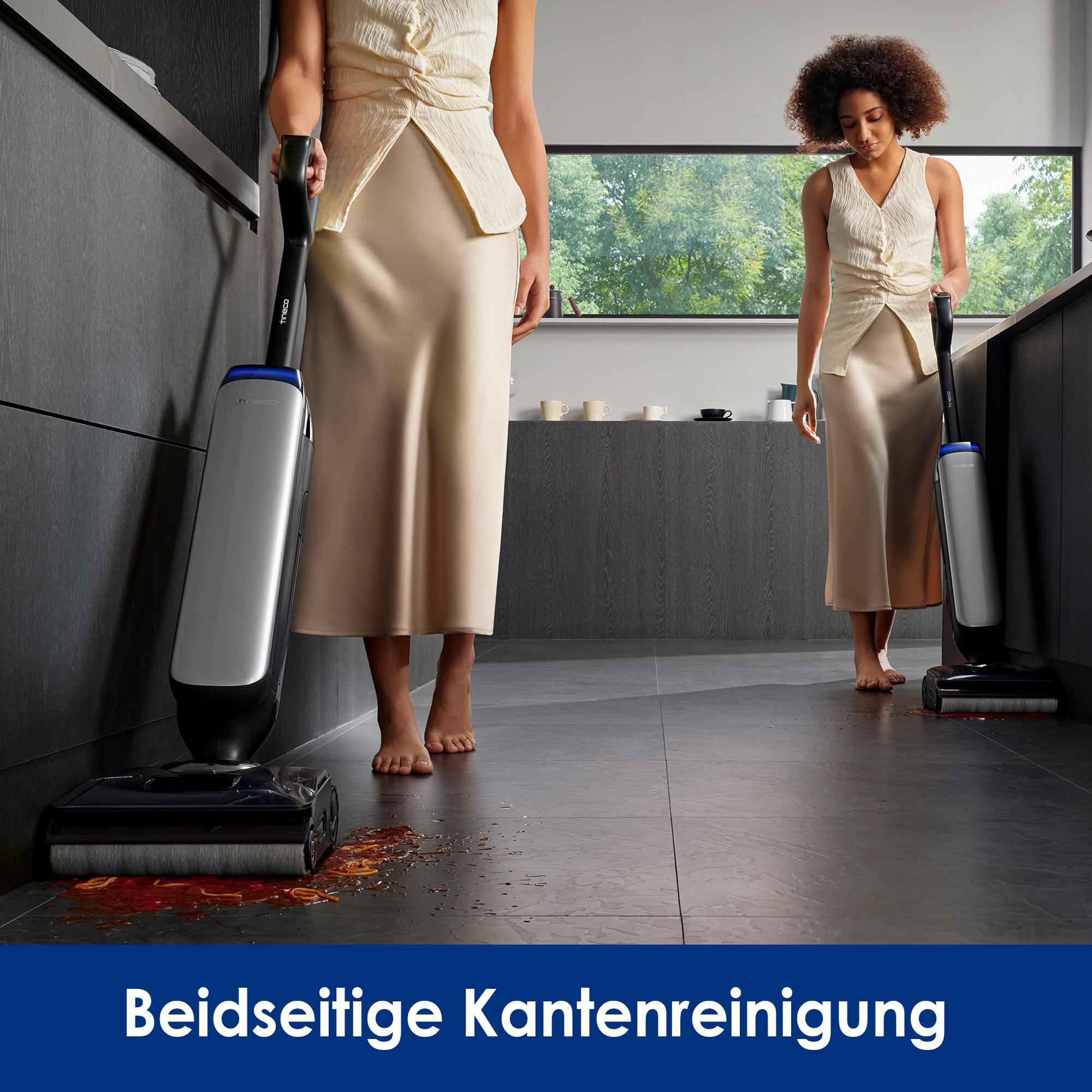 Zwei Frauen reinigen einen Boden mit einem Staubsauger. Rote Flüssigkeit ist am Boden.