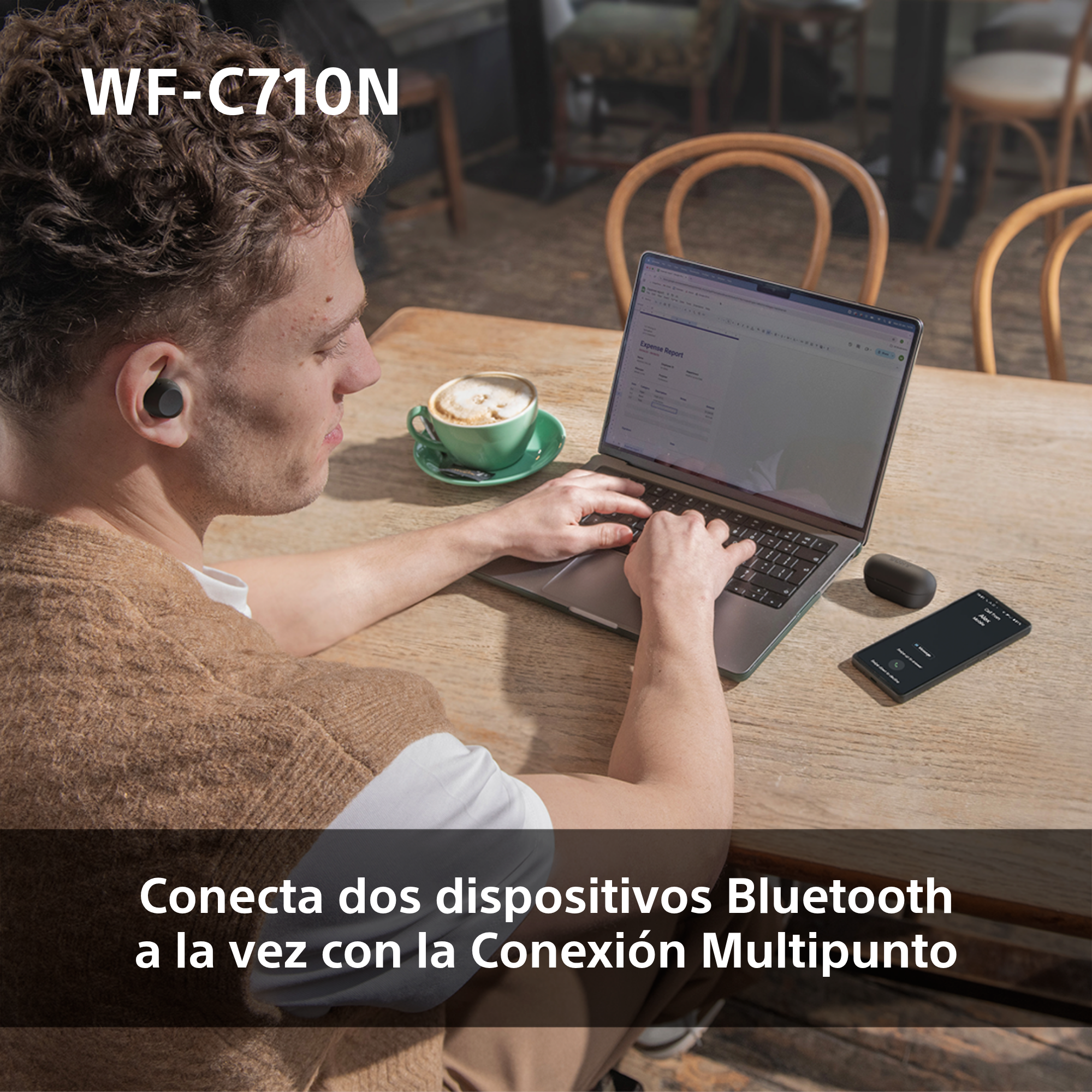 Un hombre usando una laptop, con auriculares, y una taza de café en la mesa.