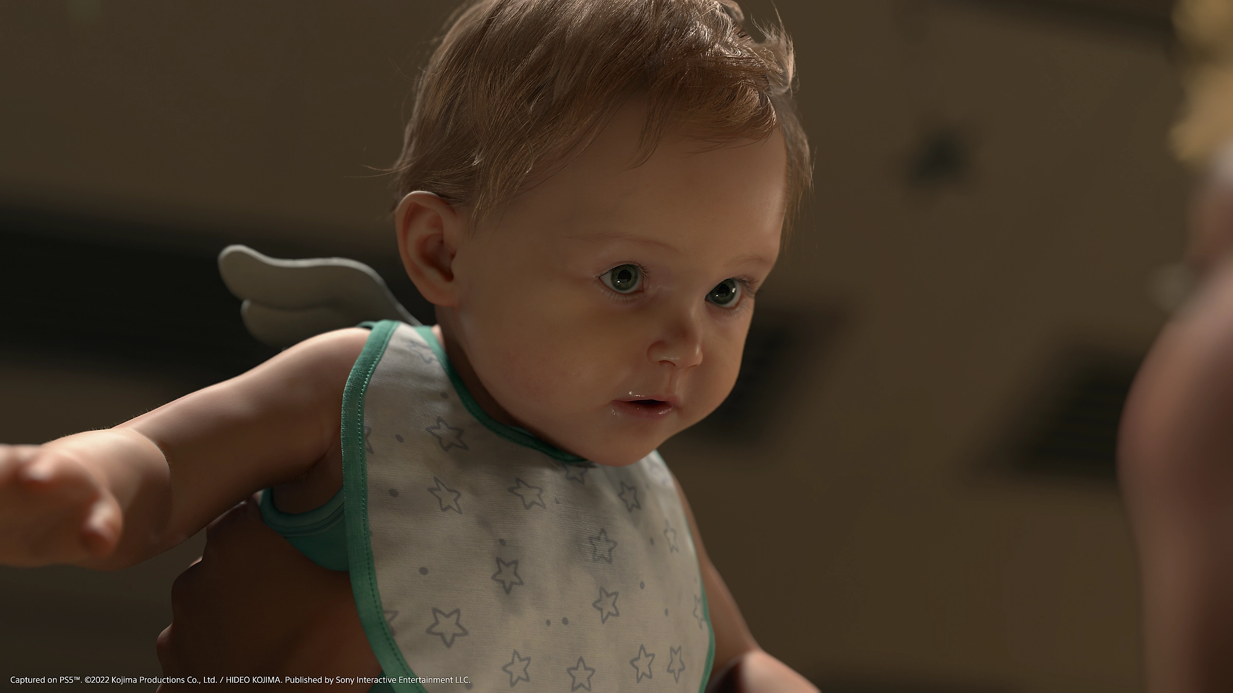Gros plan d'un bébé avec un bavoir, tenu par des mains. Le bébé a une expression angélique.