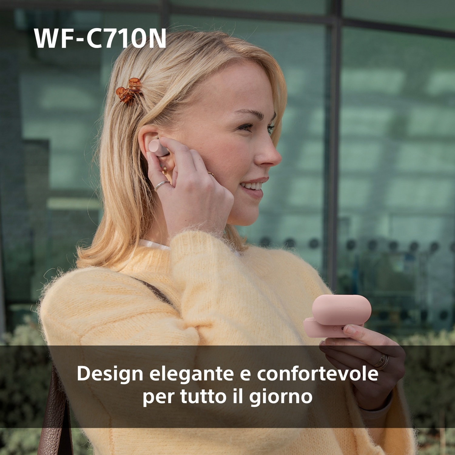 Donna con auricolari in città, tiene una custodia.